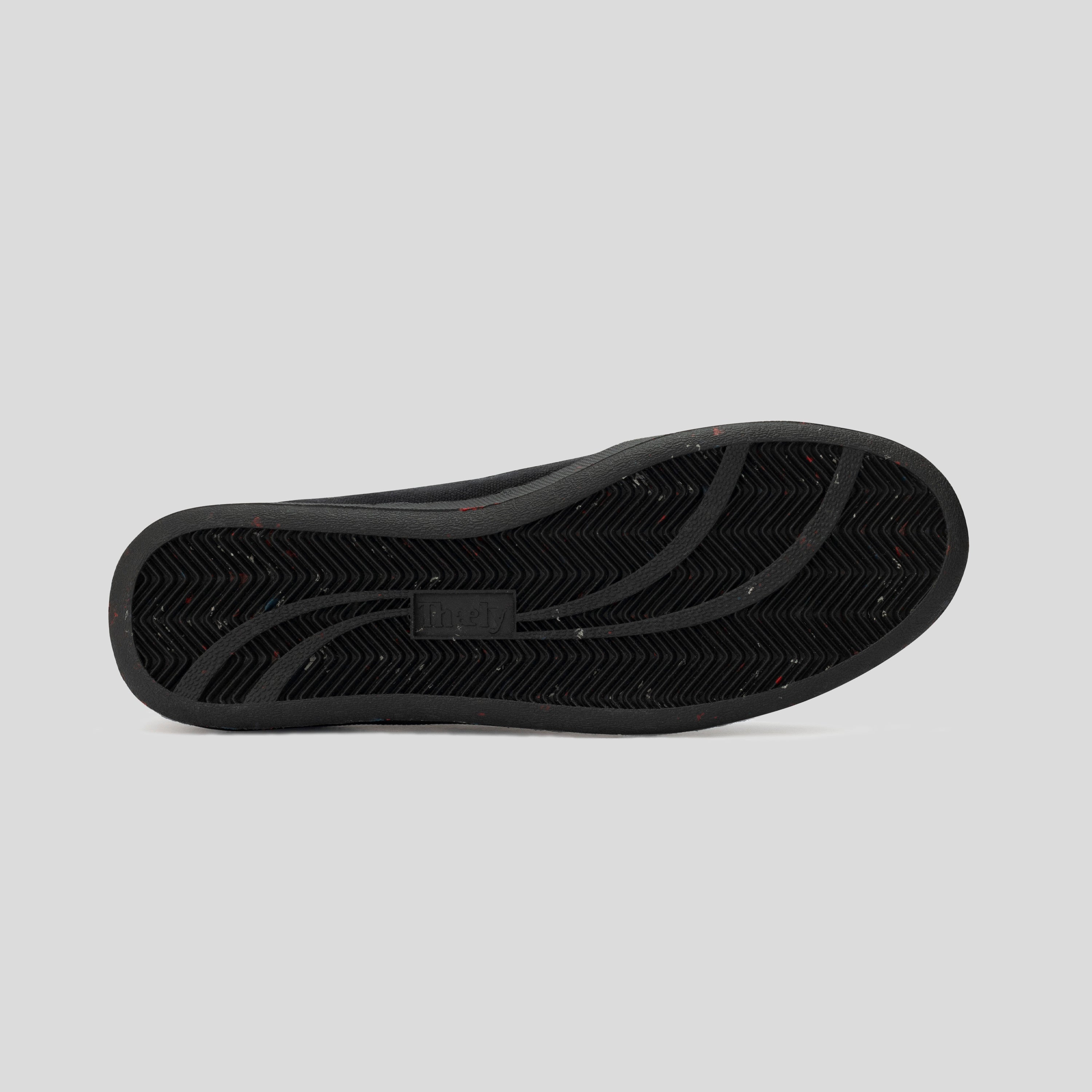 black sneaker sole with herringbone tread pattern and subtle speckled details on grey background