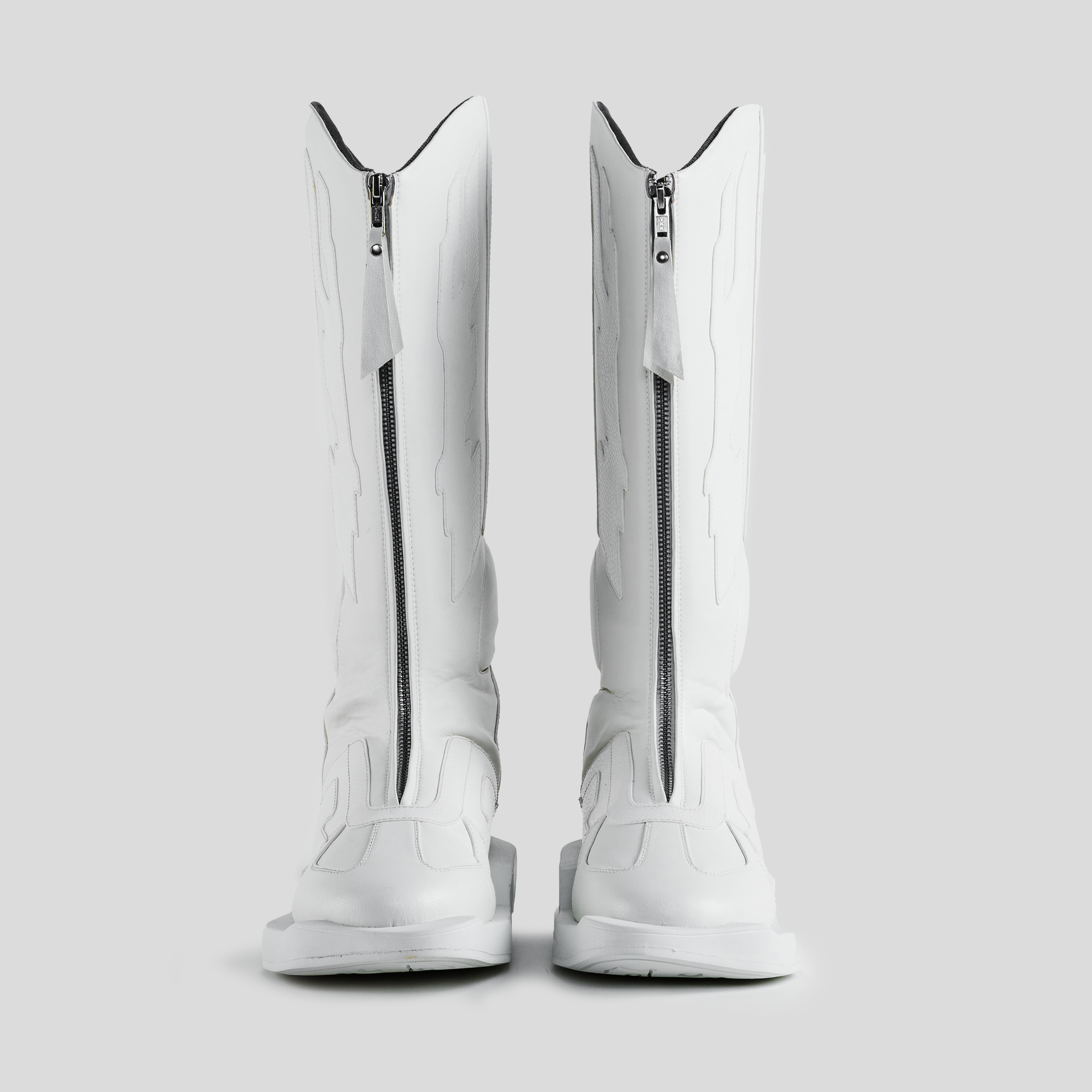White knee-high streetwear boots with front zippers and embossed detailing on a gray background.