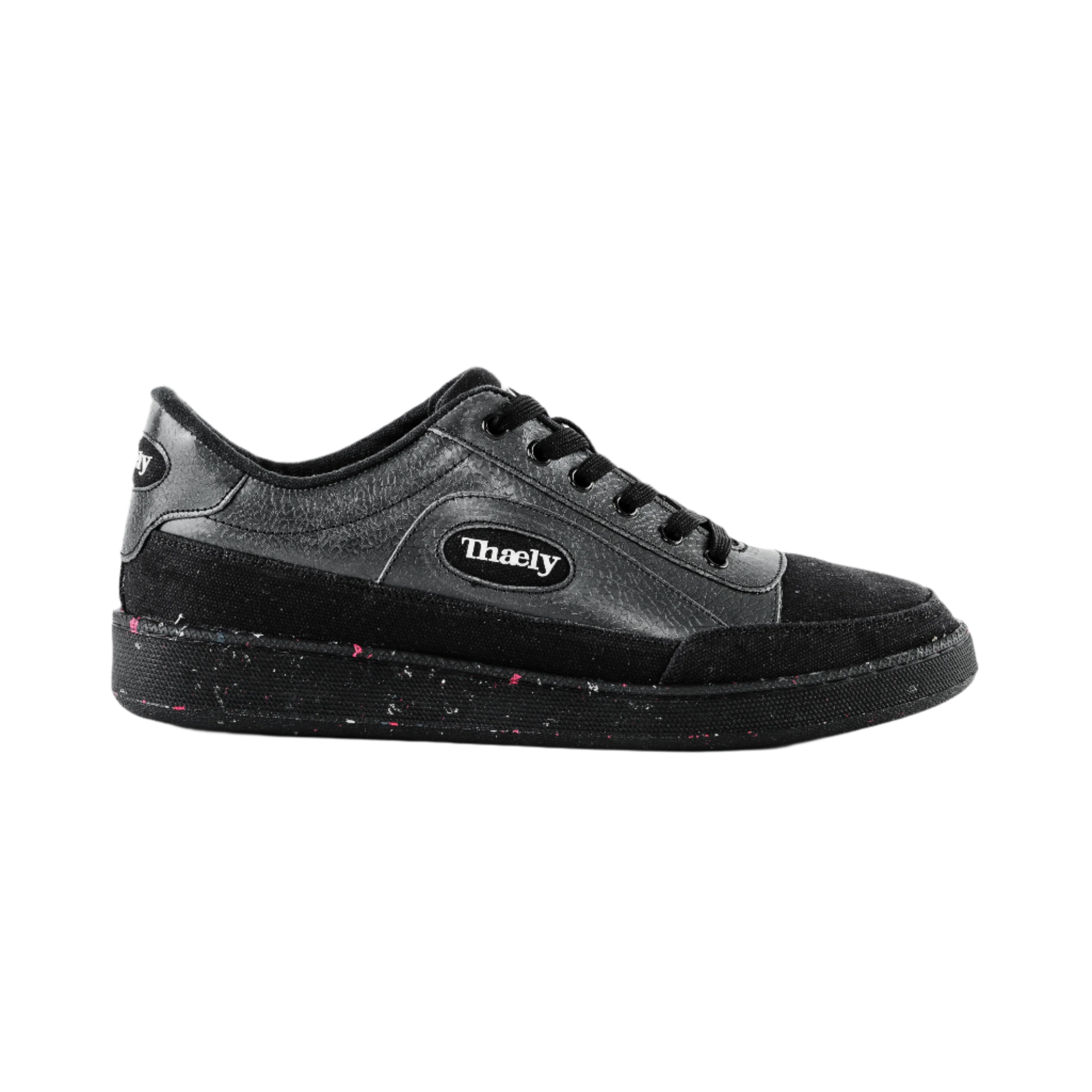 Black low-top streetwear sneaker with speckled sole and Thaely logo on the side