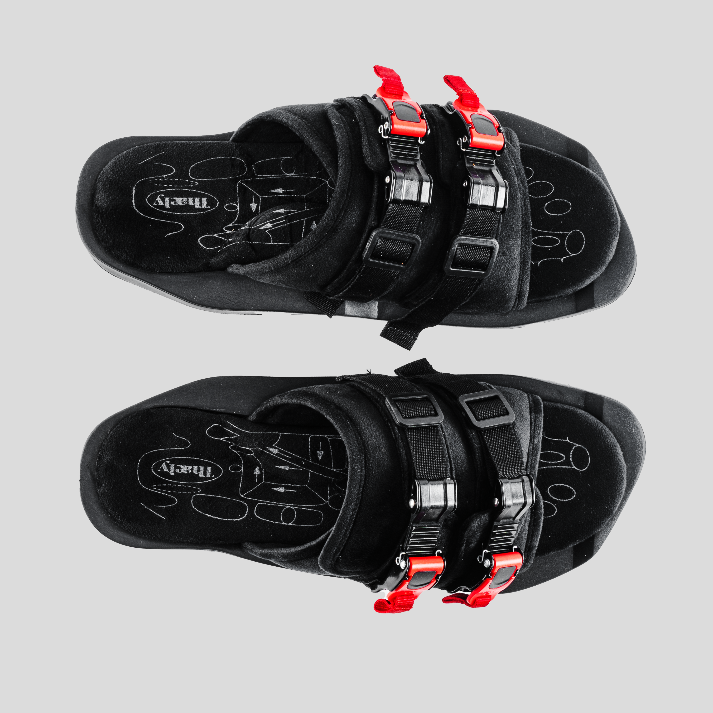 Black streetwear sandals with red buckle straps and graphic insoles, top view