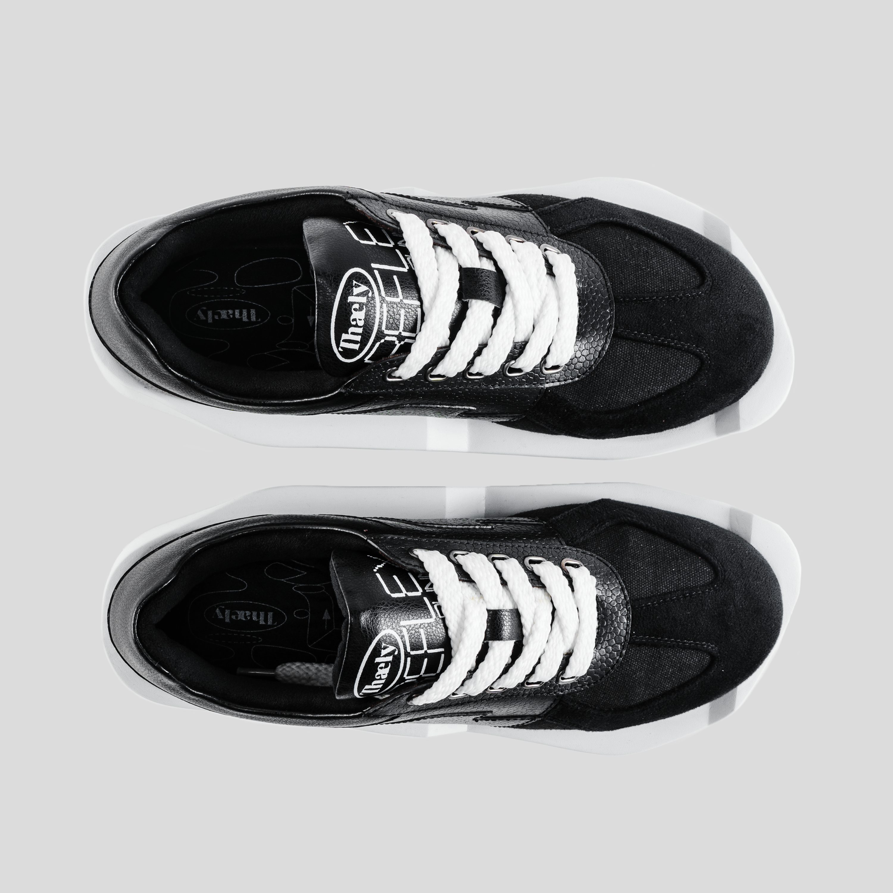 Black and white streetwear sneakers with textured panels and bold white laces, top view.