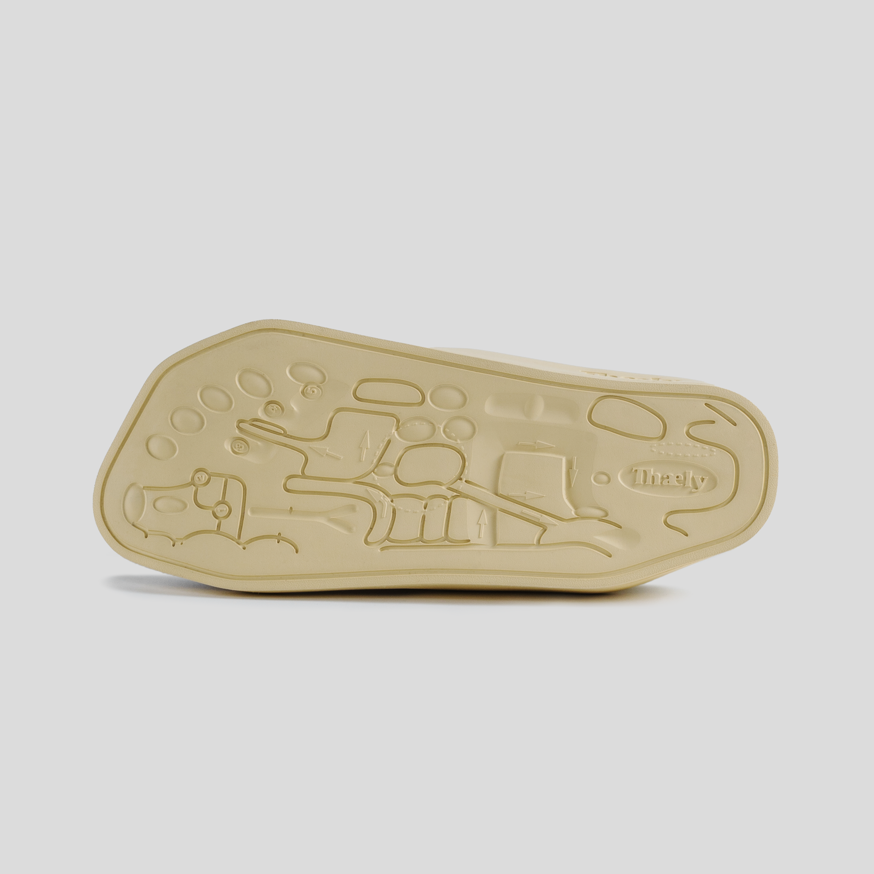 Close-up of beige sneaker outsole with unique embossed pattern and textured sole design.