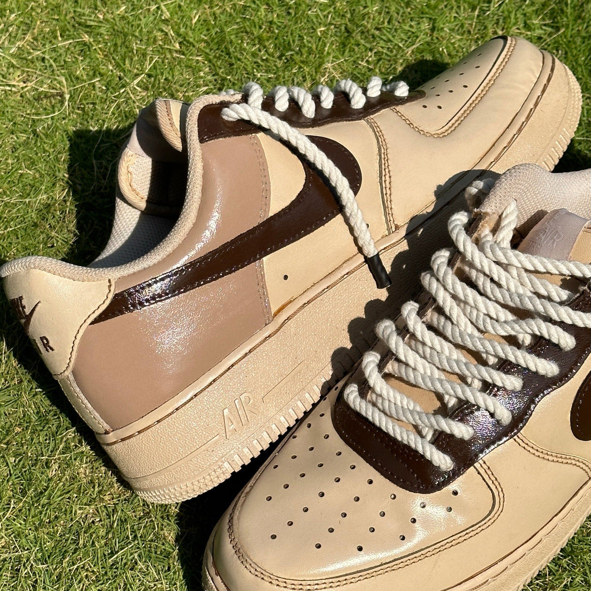 Beige and brown Nike Air Force 1 sneakers with thick rope laces on grass
