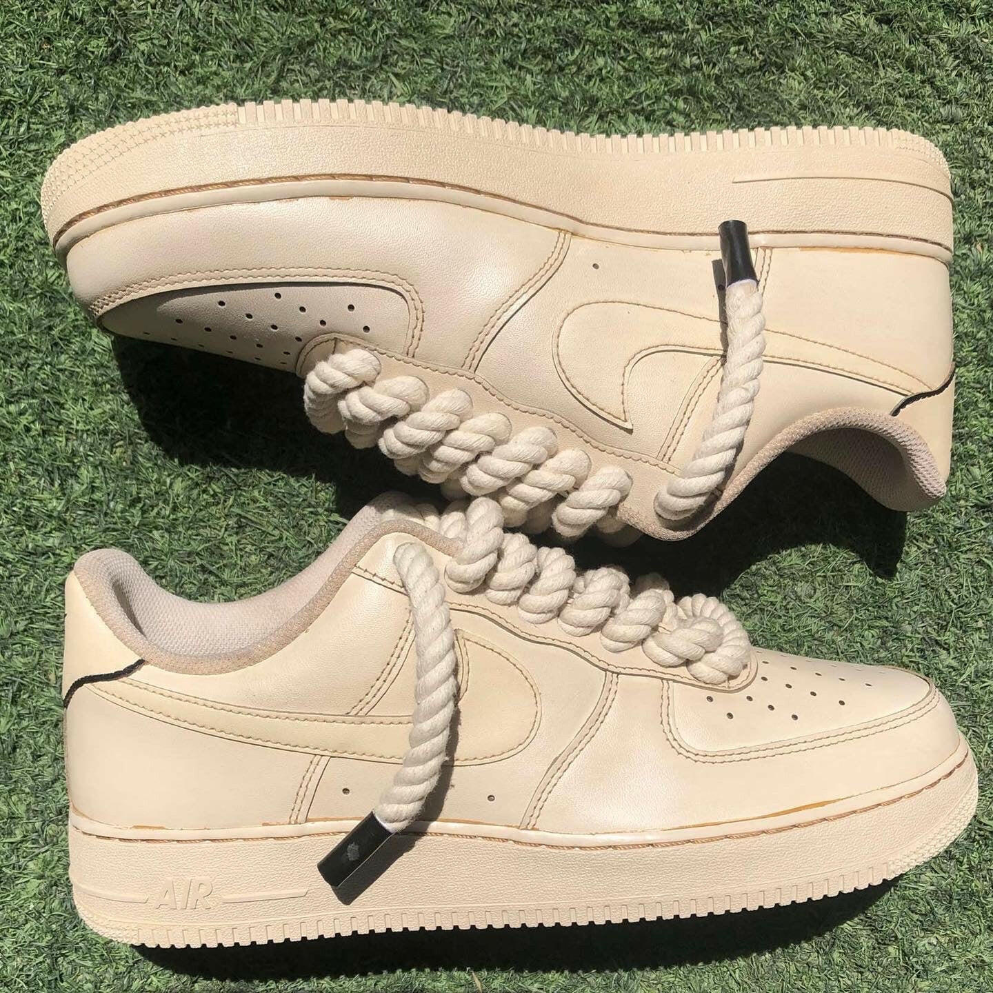 Cream low-top sneakers with rope laces on grass, streetwear luxury footwear