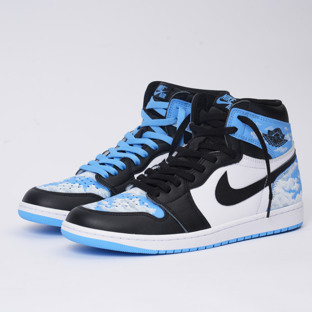 Black and white high-top sneakers with blue cloud design, blue soles, and mismatched laces.