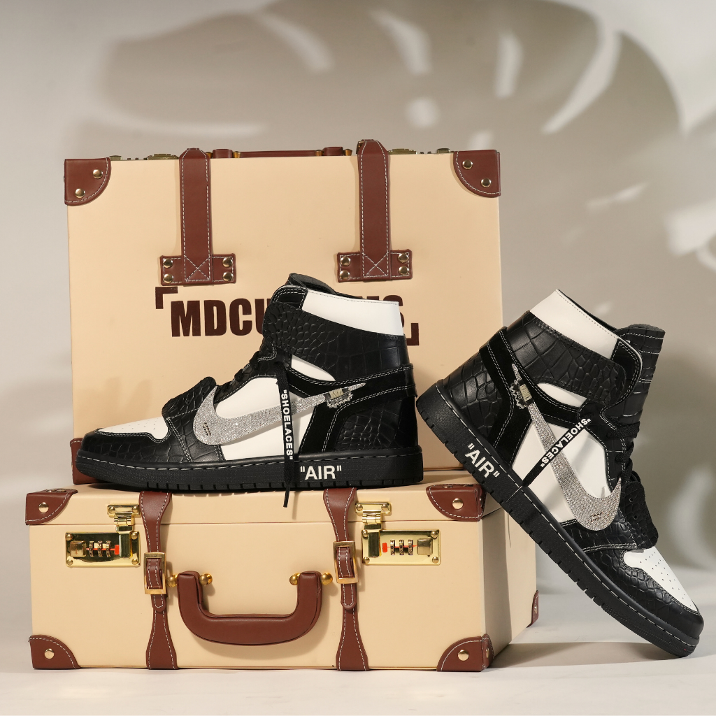 Black and white high-top sneakers with textured pattern and silver swoosh on travel case