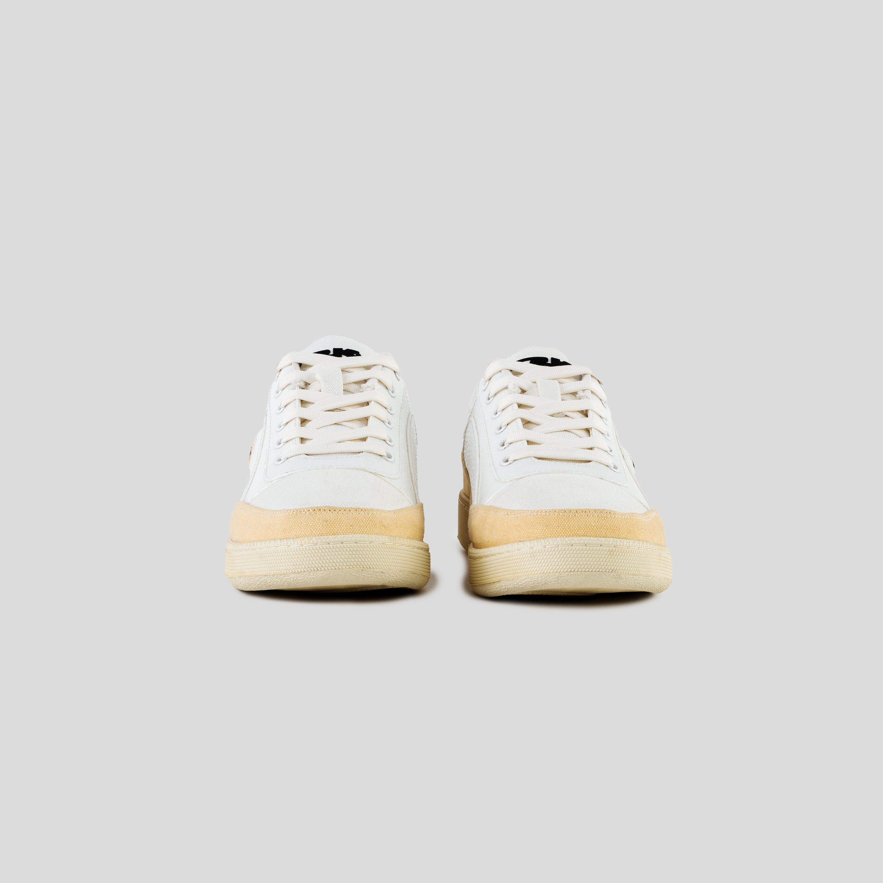 Beige and white low-top streetwear sneakers with suede accents on a neutral background