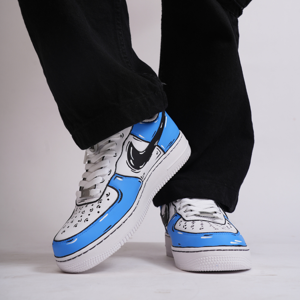 White and blue streetwear sneakers with cartoon-style design, worn with black pants