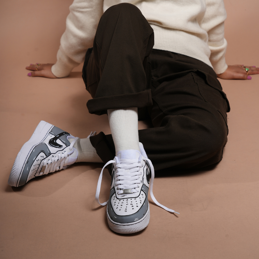 Person wearing brown pants, white socks, and designer streetwear sneakers with black accents