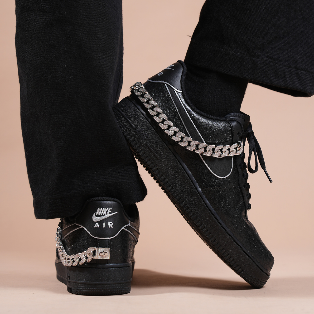 Black Nike Air Force 1 sneakers with silver chain accessory, streetwear style