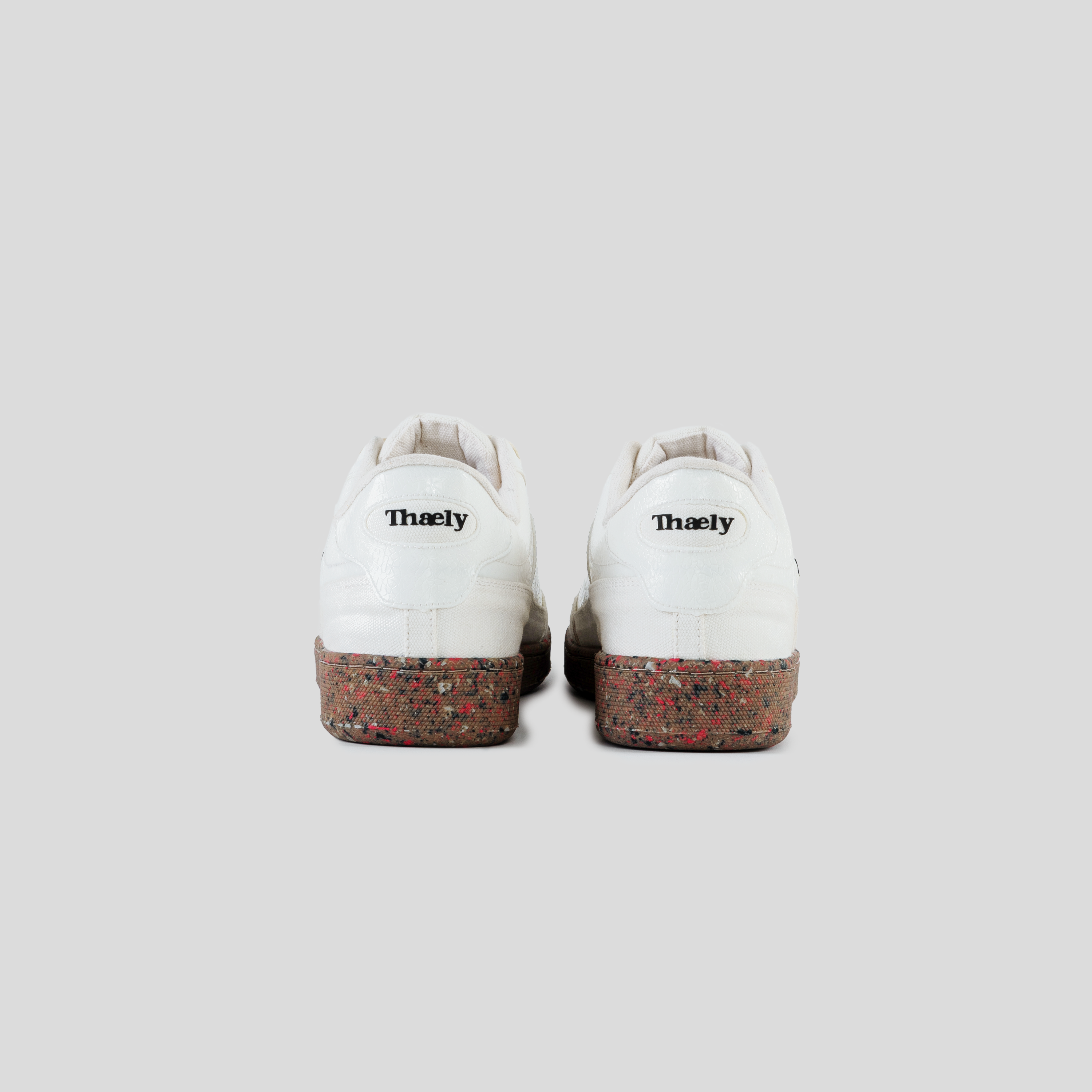 White Thaely sneakers with speckled brown soles, rear view on grey background