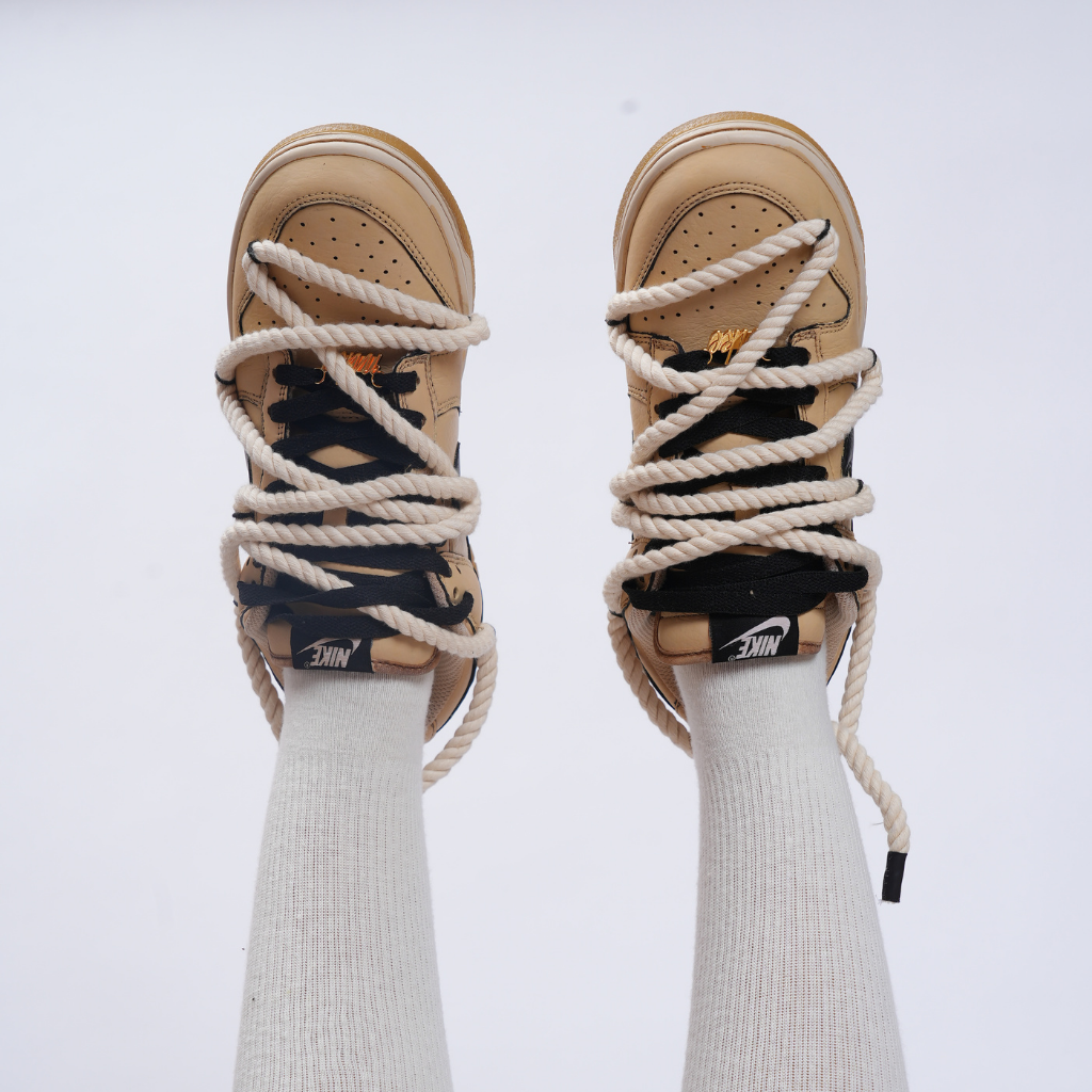 Beige Nike sneakers with oversized rope laces and white crew socks, streetwear style