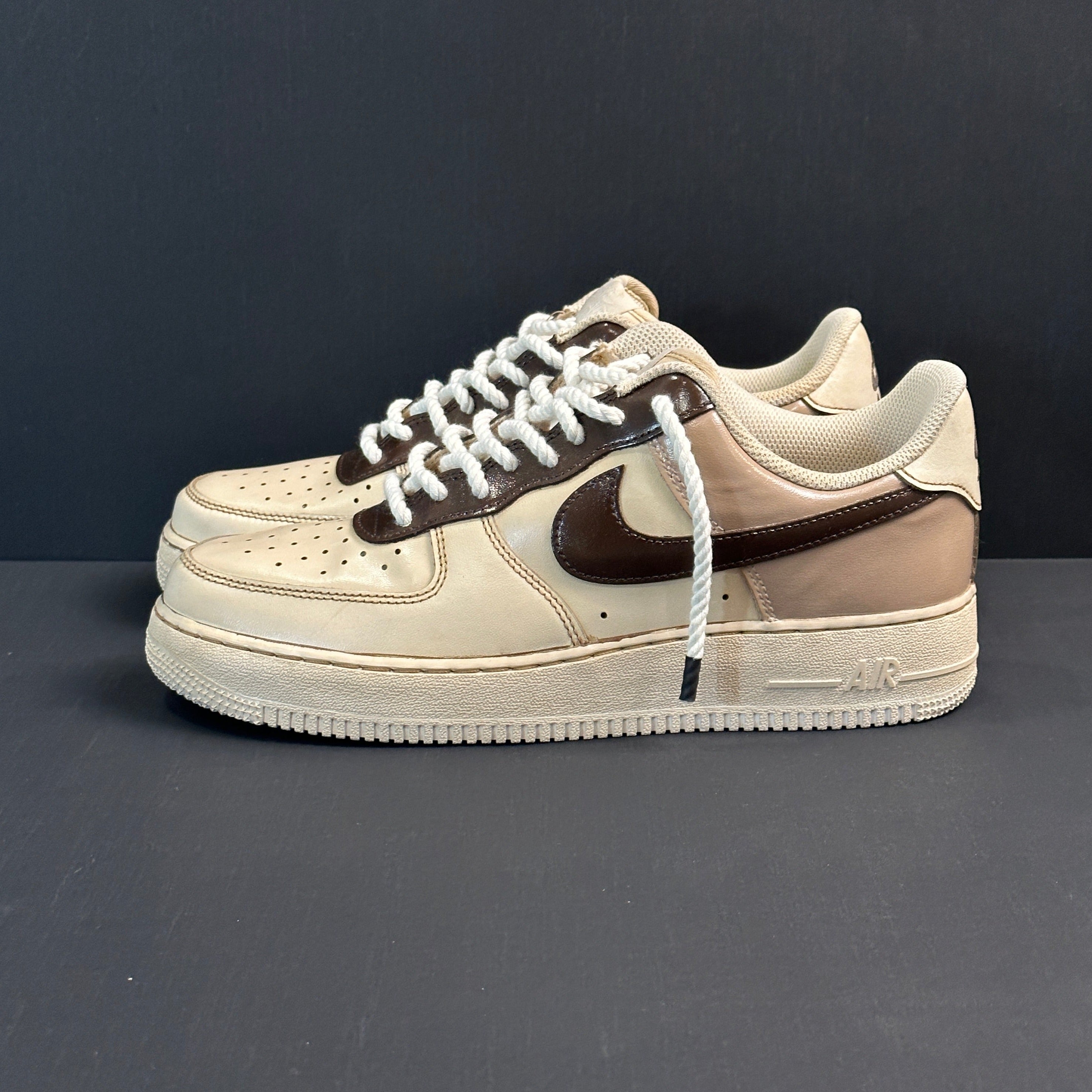 Beige and brown Nike Air Force 1 sneakers with rope laces on a dark background