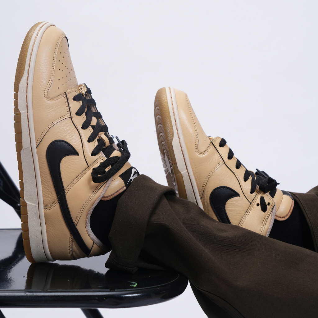 Beige and black leather streetwear sneakers with black laces worn with dark pants