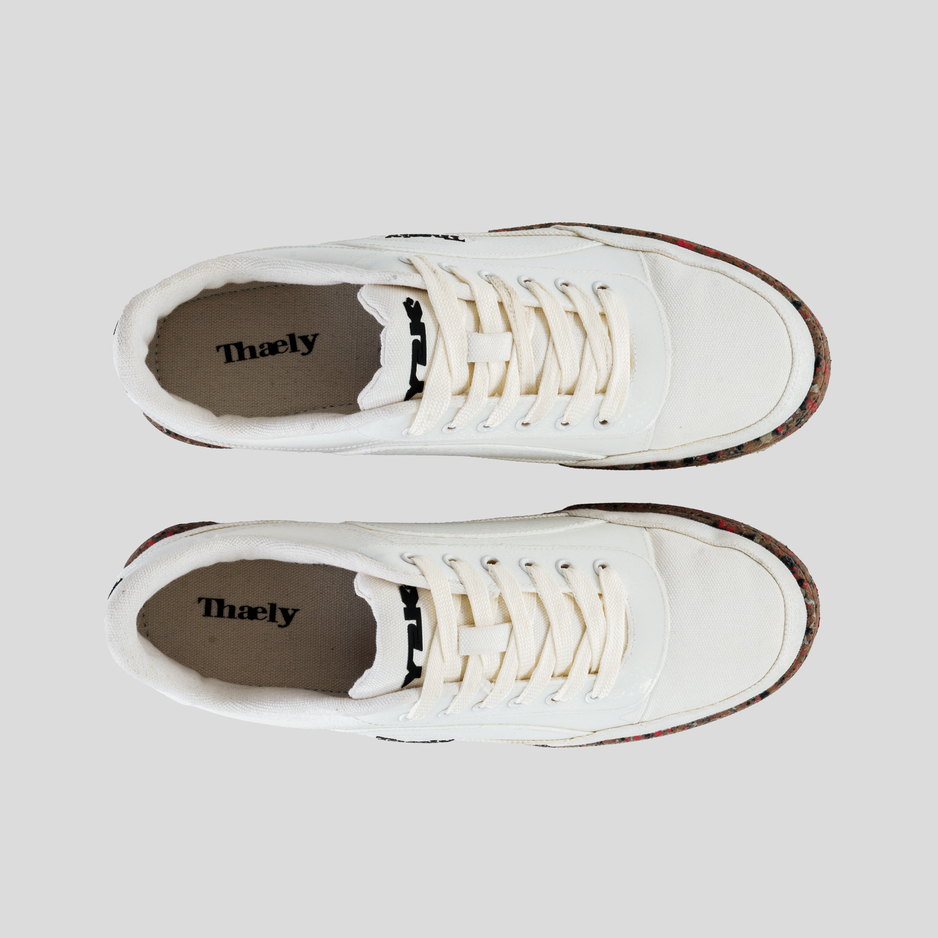 Top view of white streetwear sneakers with recycled multicolor soles and Thaely branding