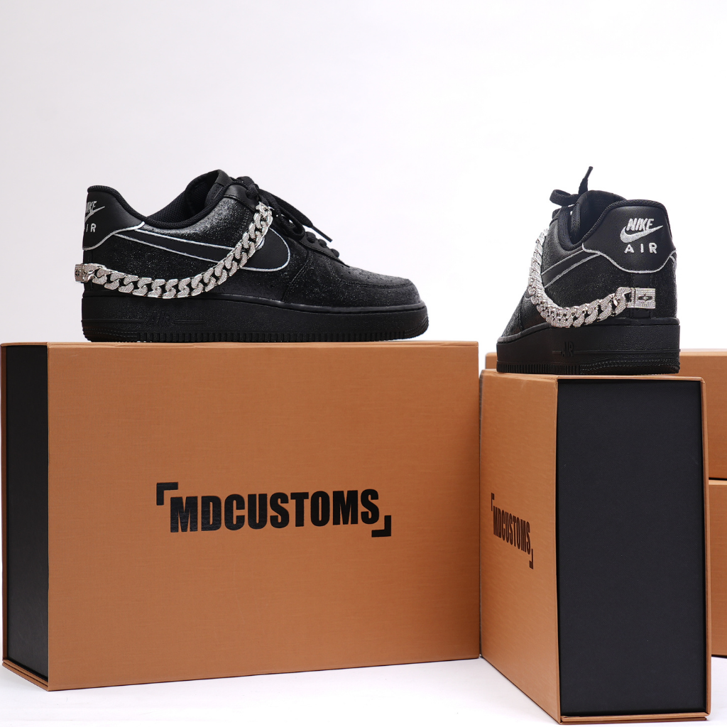Black custom Nike Air sneakers with silver chain detail on display boxes, streetwear footwear