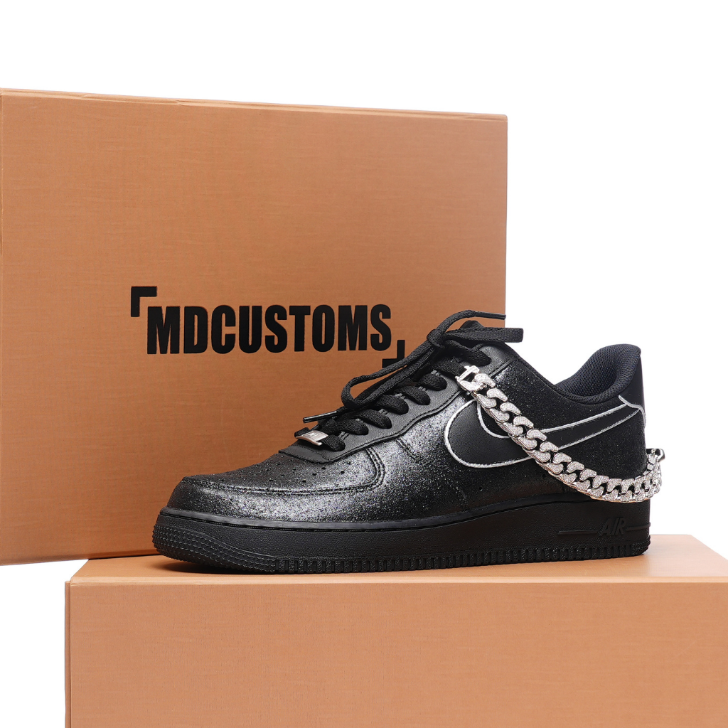 Black custom streetwear sneaker with metallic chain detail, displayed on brown shoe boxes