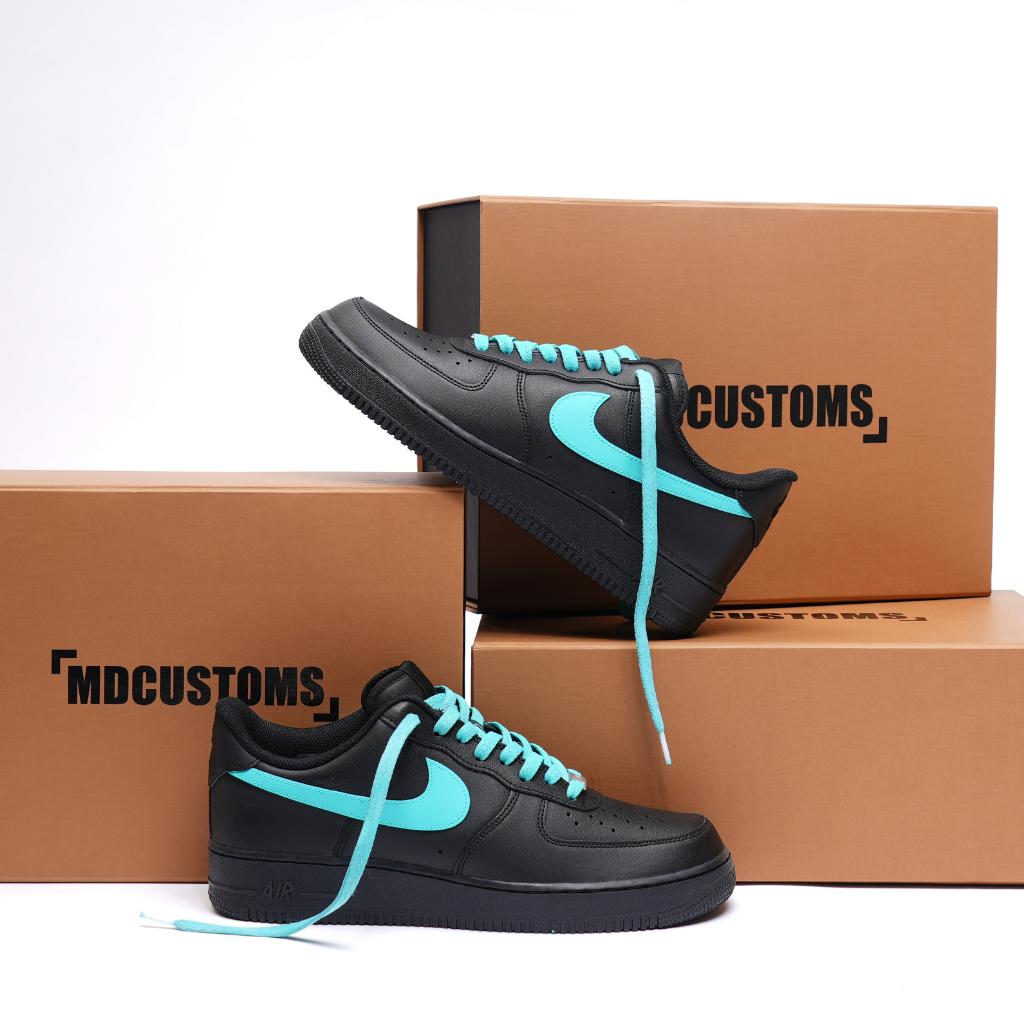 Black custom sneakers with teal swoosh and laces, displayed on brown MDCUSTOMS shoe boxes
