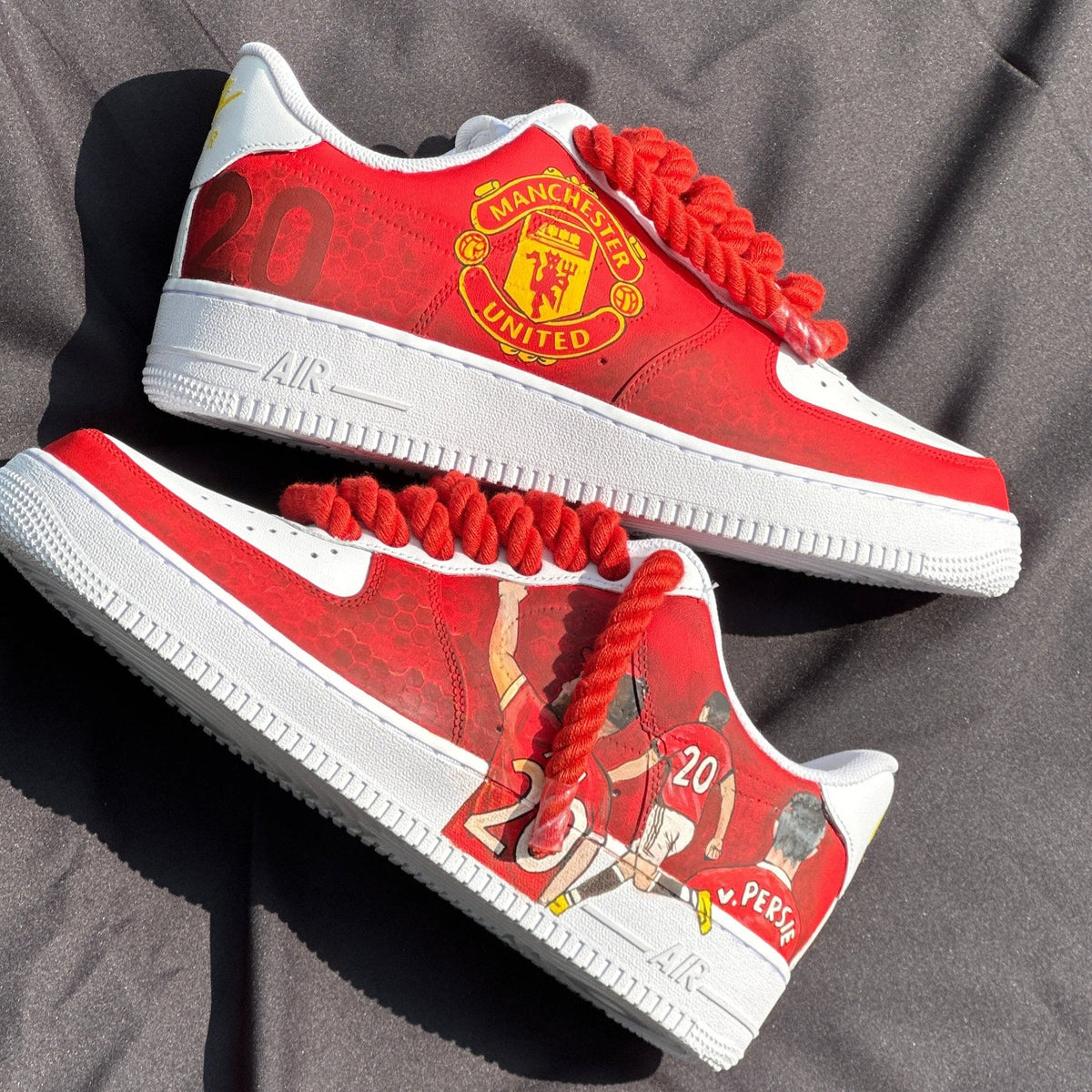 Custom red and white sneakers with Manchester United logo, celebrating Van Persie, on fabric background.