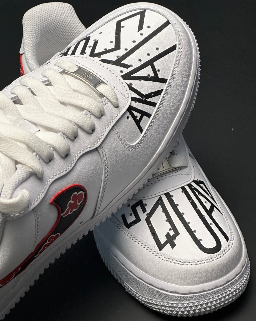 White streetwear sneakers with bold black graphic text on toe and red cloud design on swoosh