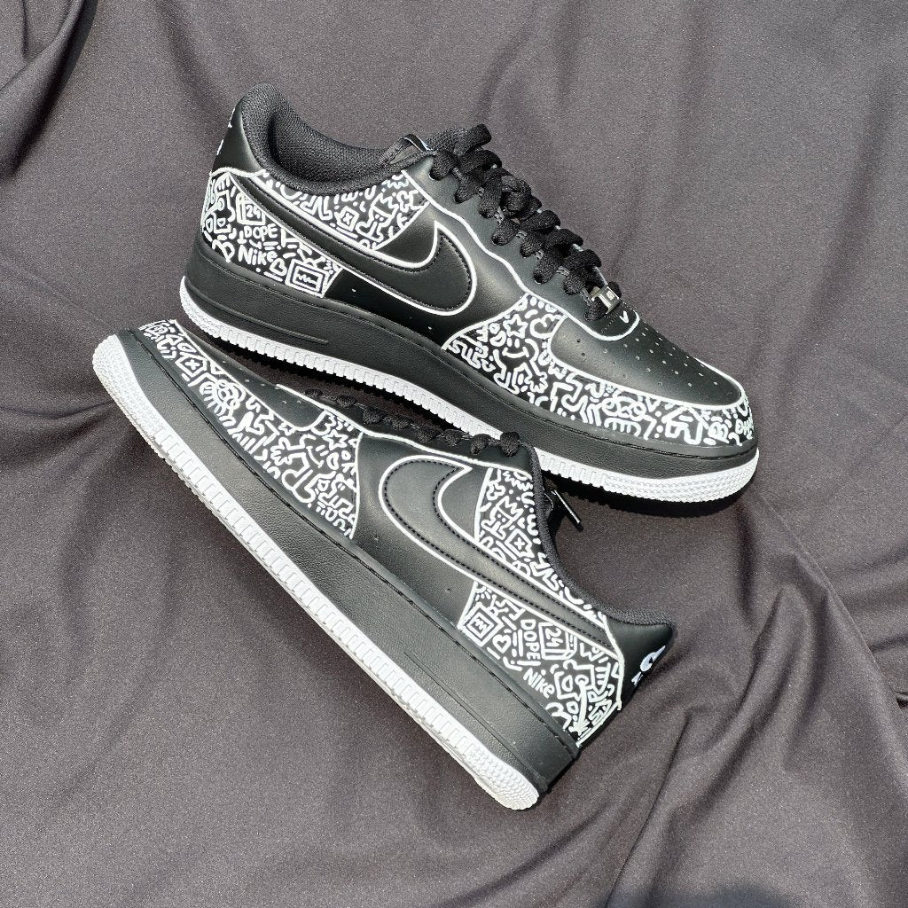 Black and white streetwear sneakers with graphic doodle patterns and white soles on fabric background