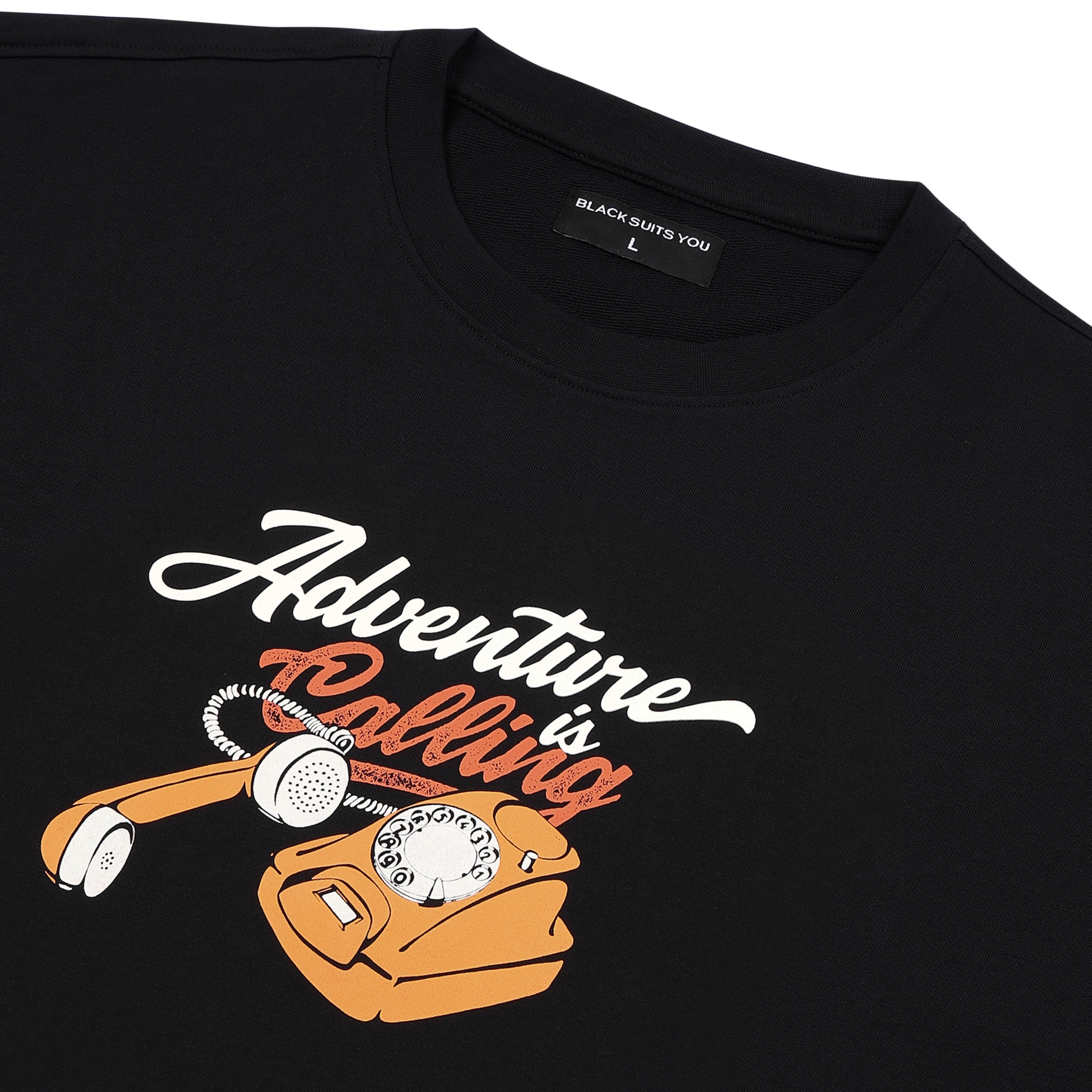 Black streetwear t-shirt with graphic of orange rotary phone and 'Adventure is Calling' text.