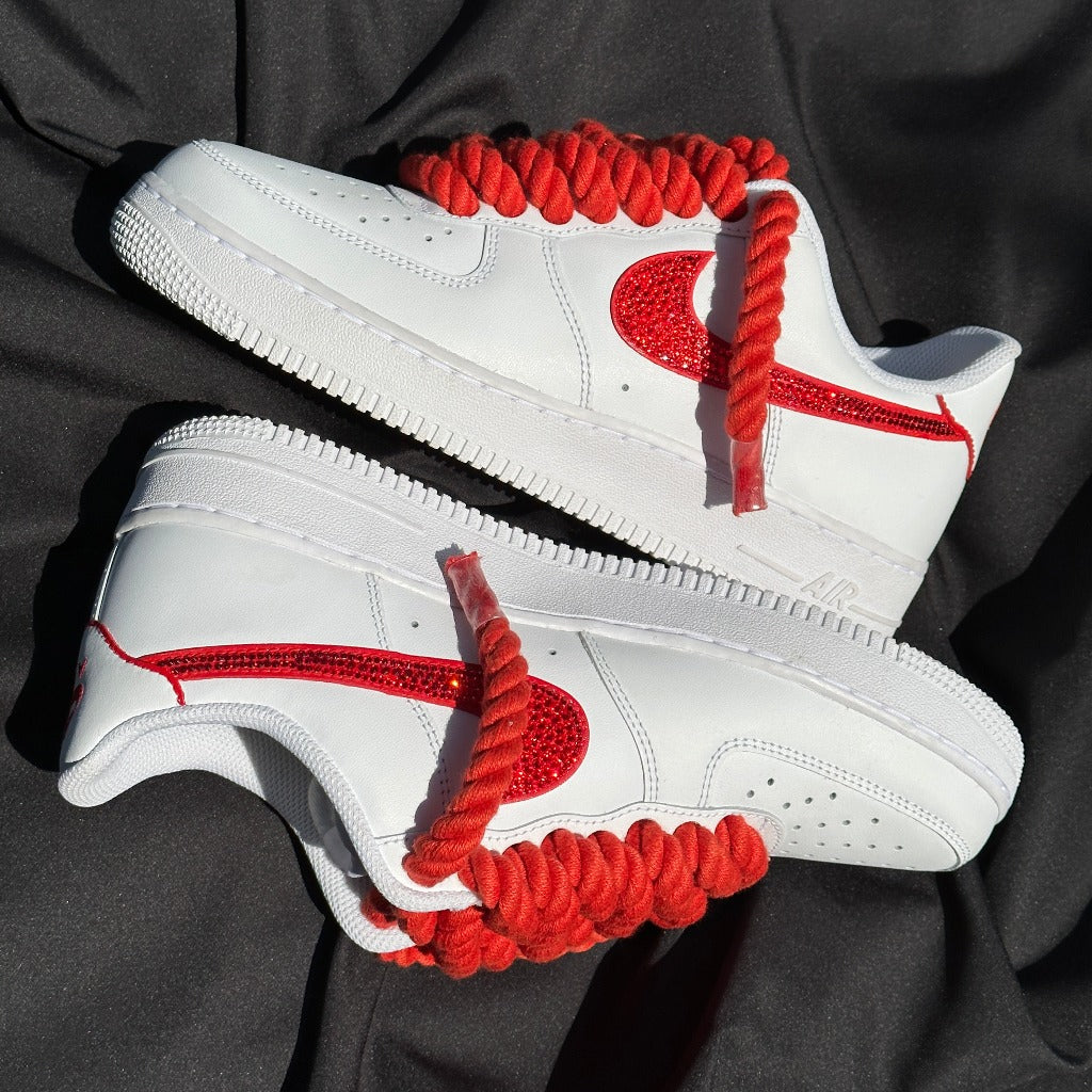 White low-top sneakers with red rope laces and red glitter swoosh, streetwear style