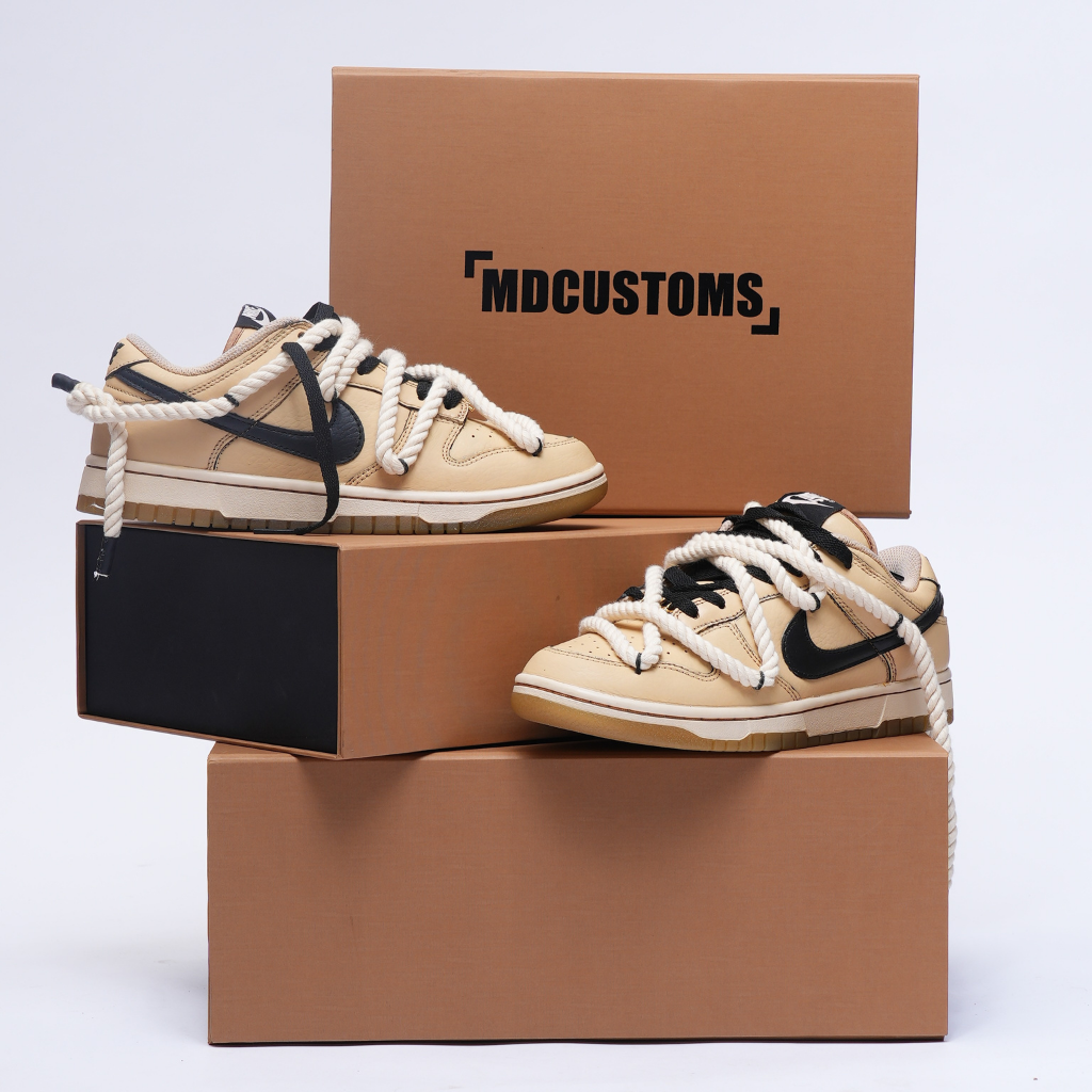 Beige and black low-top streetwear sneakers with oversized rope laces on custom shoe boxes.