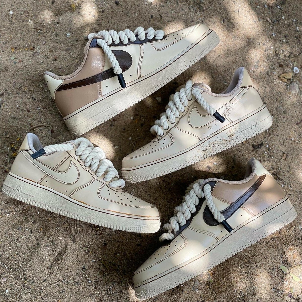 Beige and brown streetwear sneakers with chunky rope laces on sandy ground