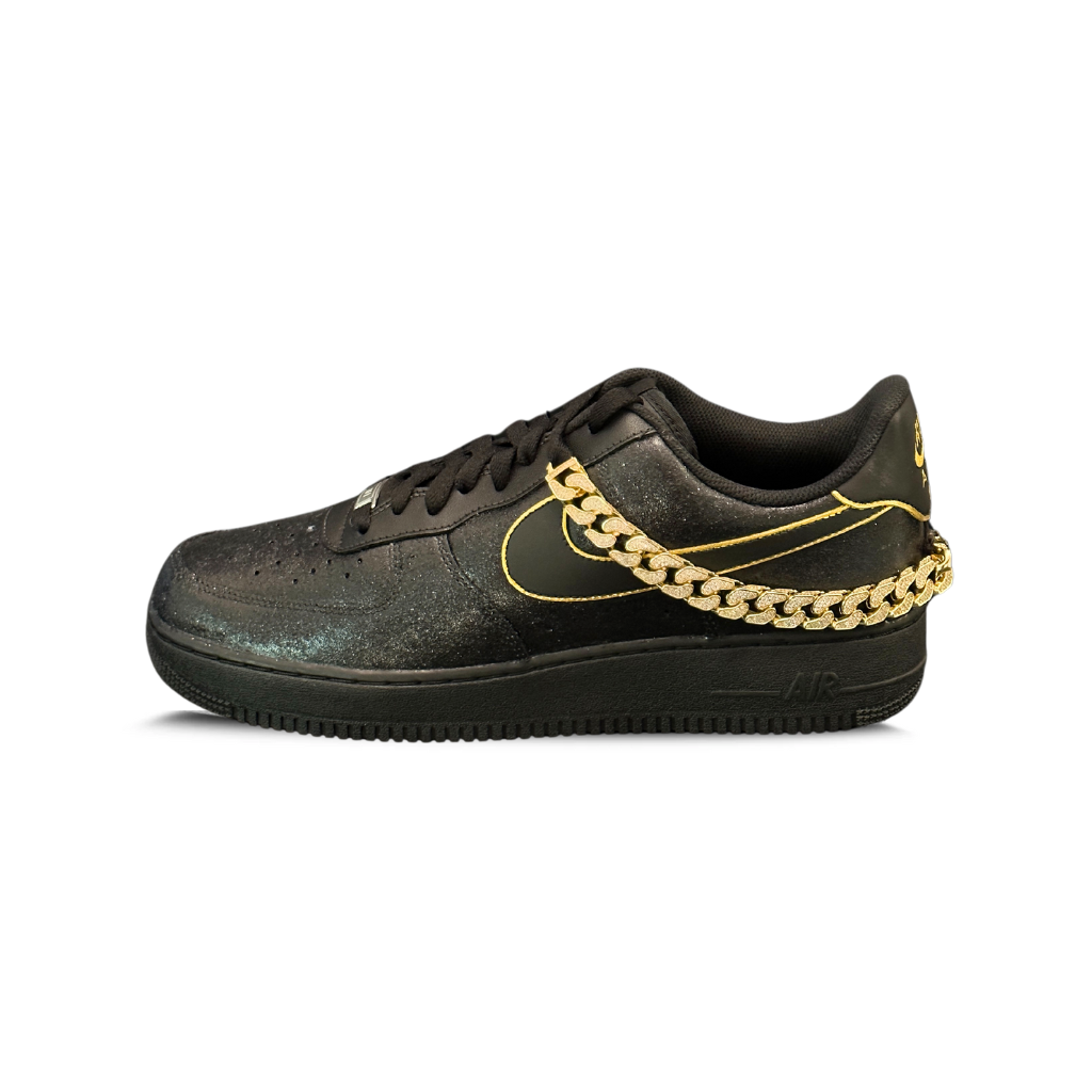 Black designer sneaker with gold accents and a gold chain on the side, streetwear style