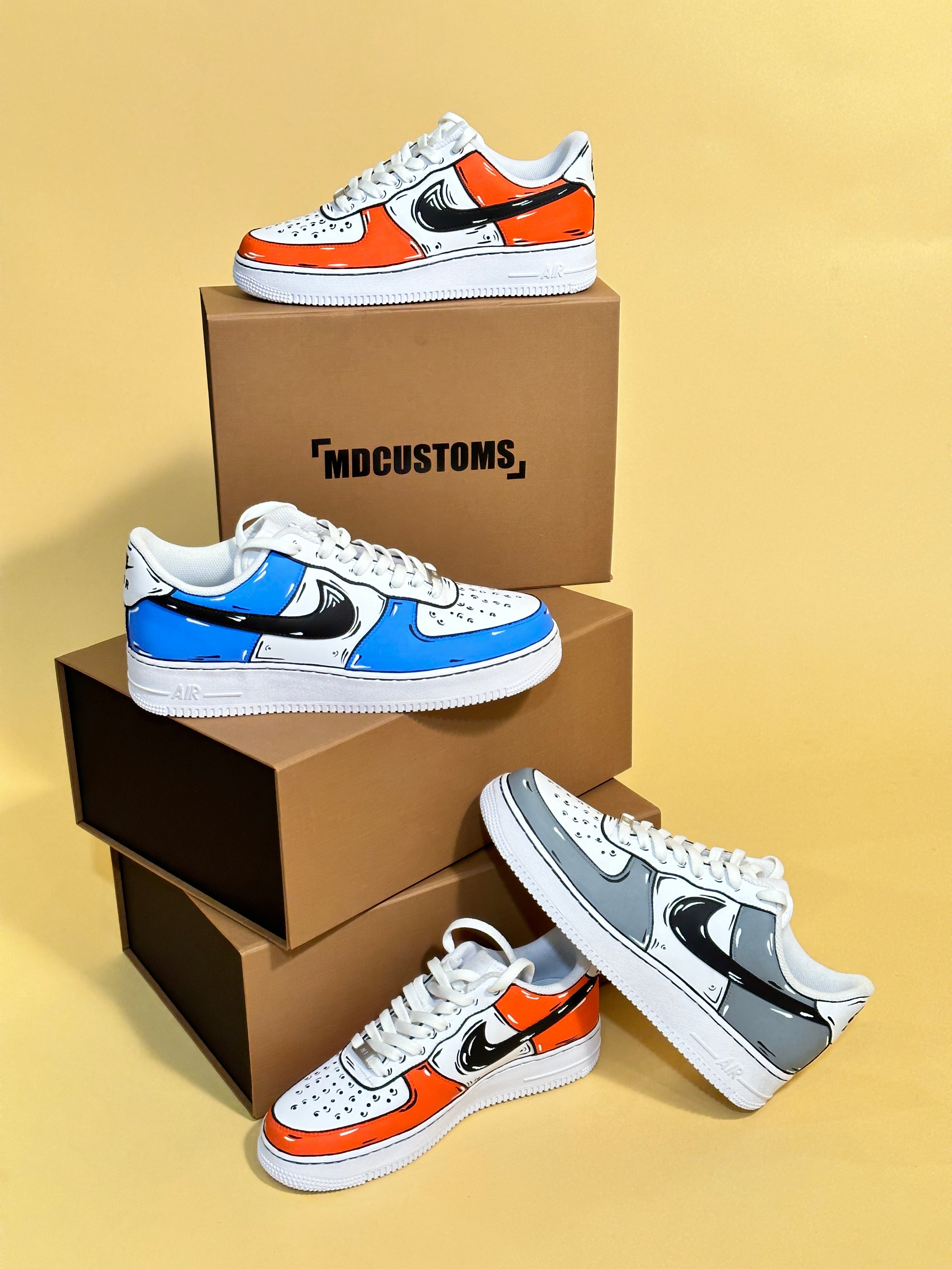 Custom cartoon-style streetwear sneakers in orange, blue, and grey with bold black details displayed on brown shoe boxes