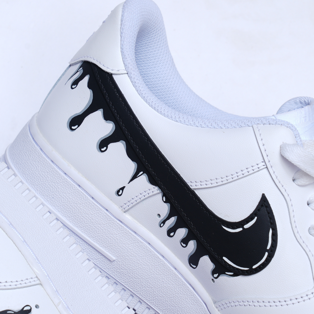 White streetwear sneaker with black drip design accent and textured sole on white background