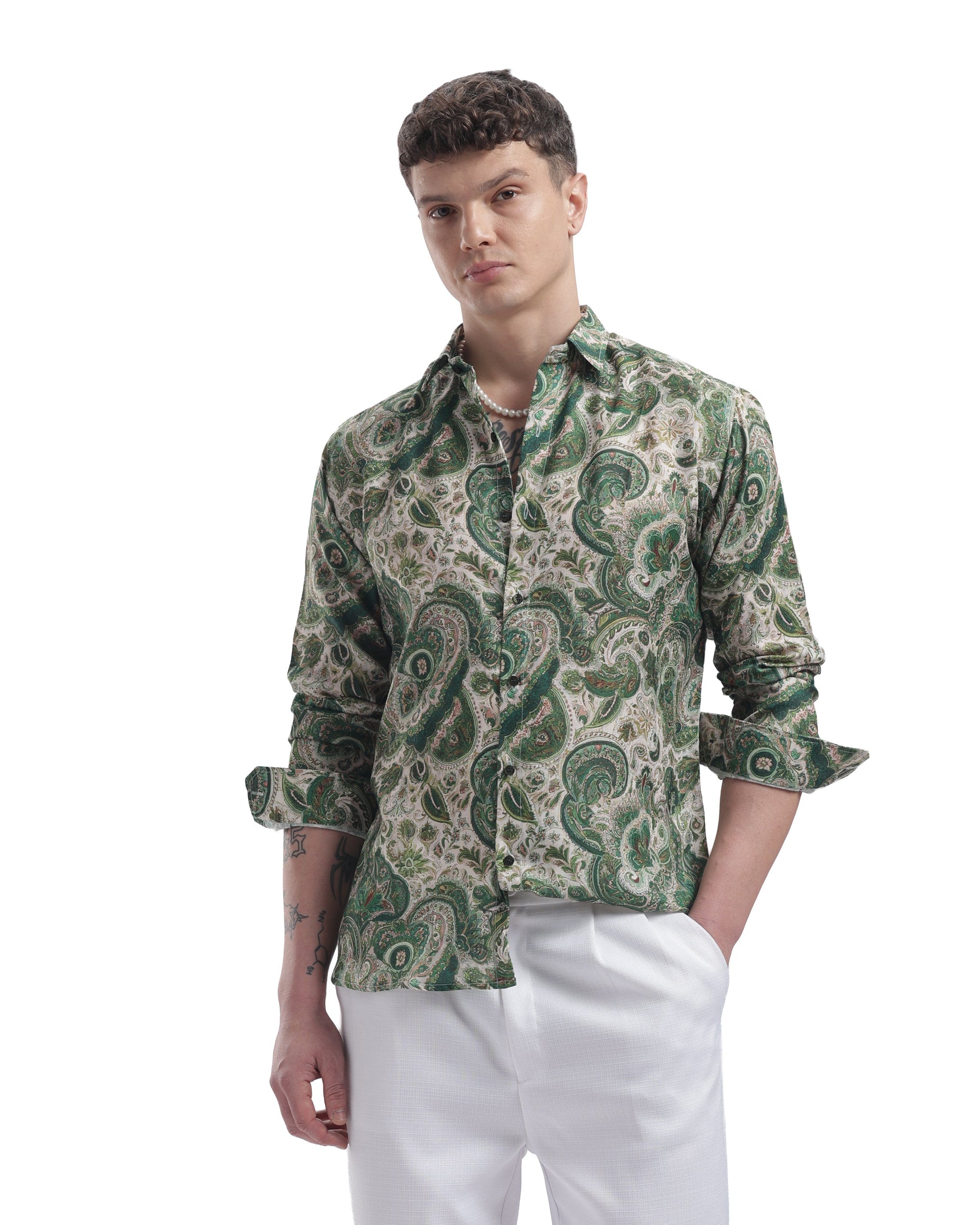 Man wearing a green patterned shirt and white pants on a white background