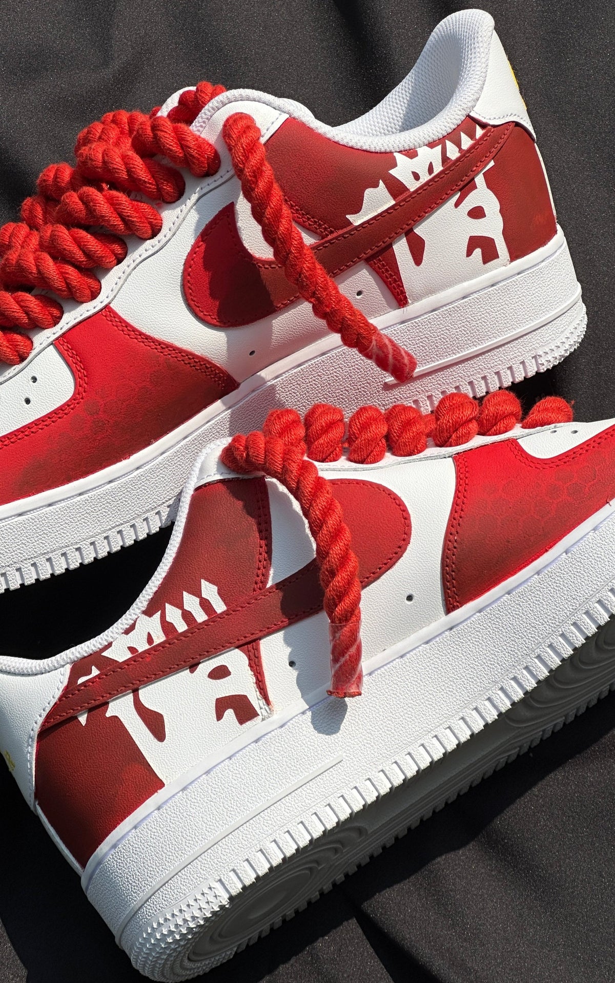 Red and white streetwear sneakers with bold graphic design and thick red laces on black fabric