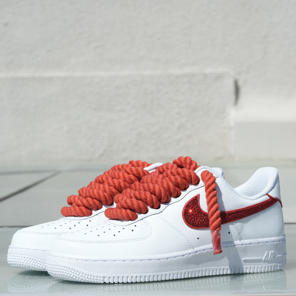White streetwear sneakers with thick red laces and red sparkling side logo on white background