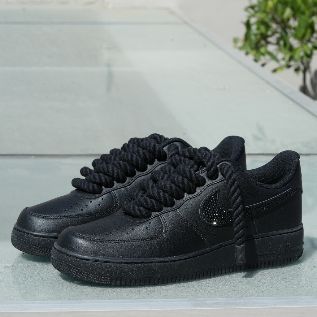 Black low-top streetwear sneakers with thick rope laces and textured Swoosh detail