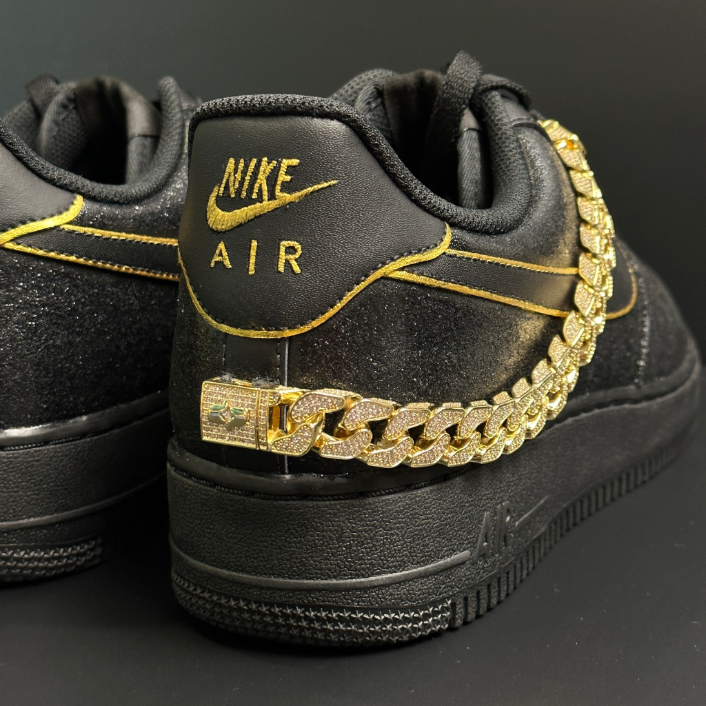 Black Nike Air sneakers with gold chain detail and yellow stitching, luxury streetwear style