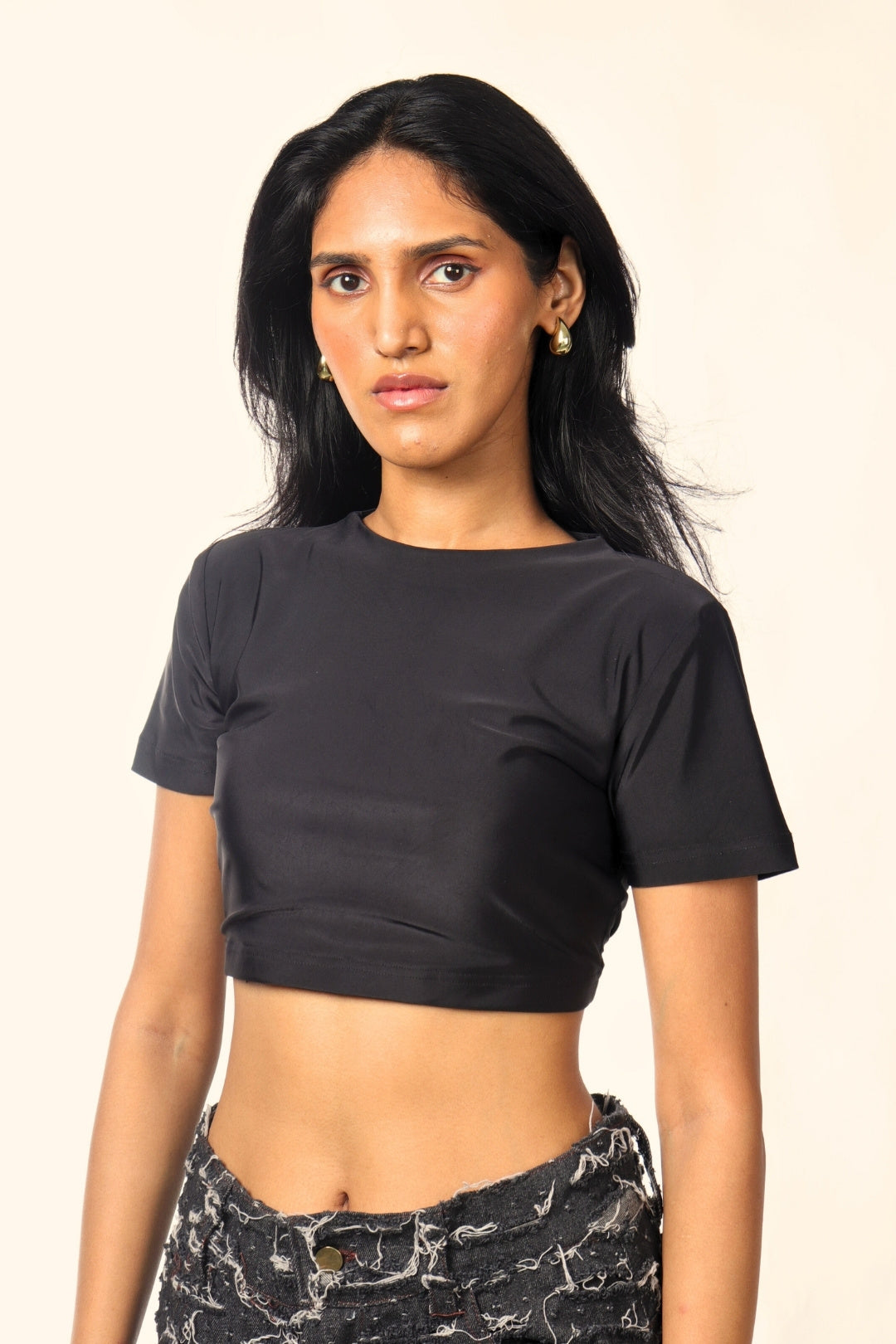 Woman wearing a black crop top and distressed black denim jeans, streetwear fashion