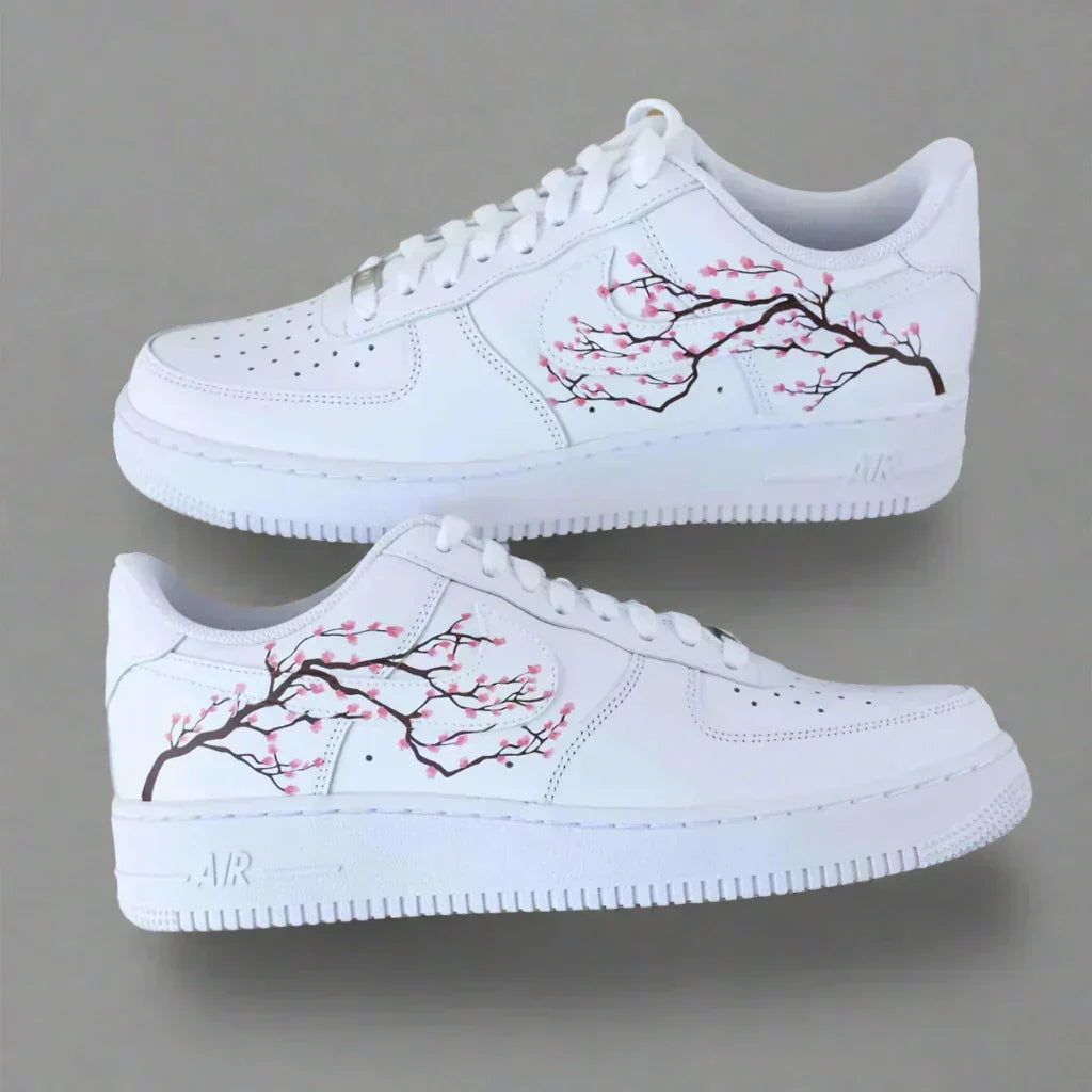 White streetwear sneakers with hand-painted cherry blossom branch design on the sides.