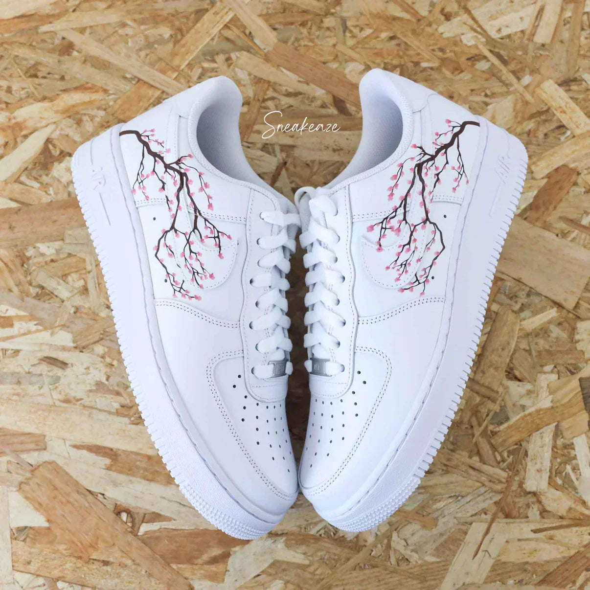 White streetwear sneakers with cherry blossom design on wooden background