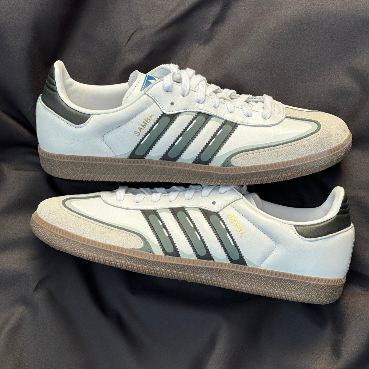 White retro sneakers with black stripes, suede toe, gum sole on black satin background