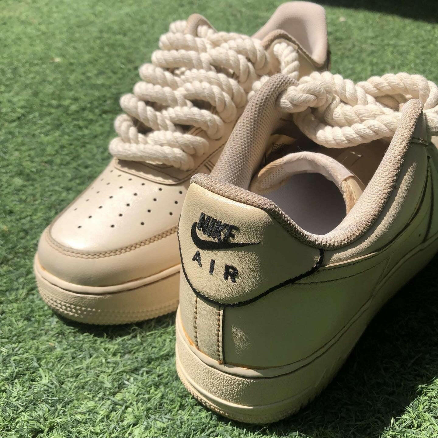 Beige Nike Air Force 1 sneakers with thick rope laces on green turf
