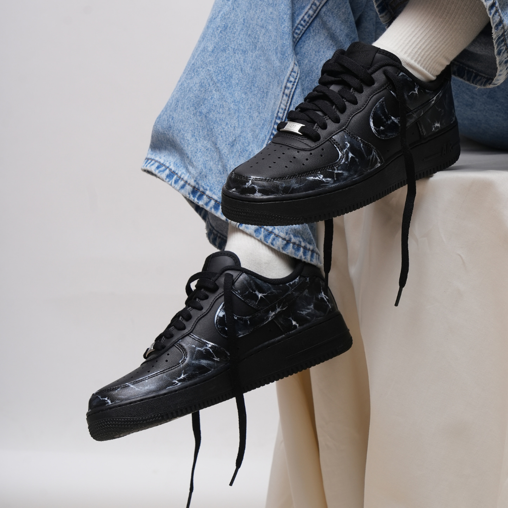 Black marble-pattern streetwear sneakers with white socks and blue jeans.