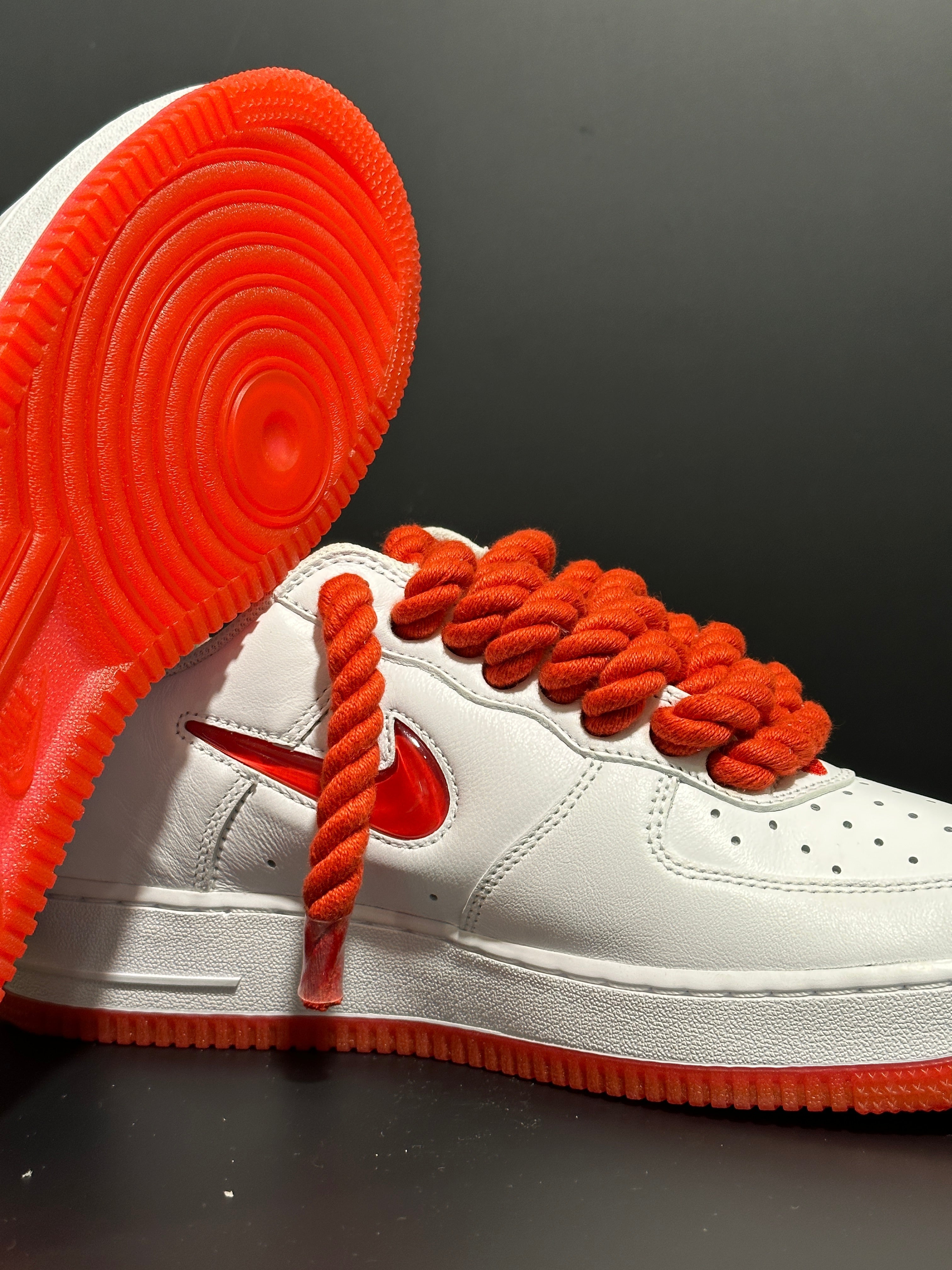 White leather sneaker with thick red rope laces and red sole, modern streetwear style