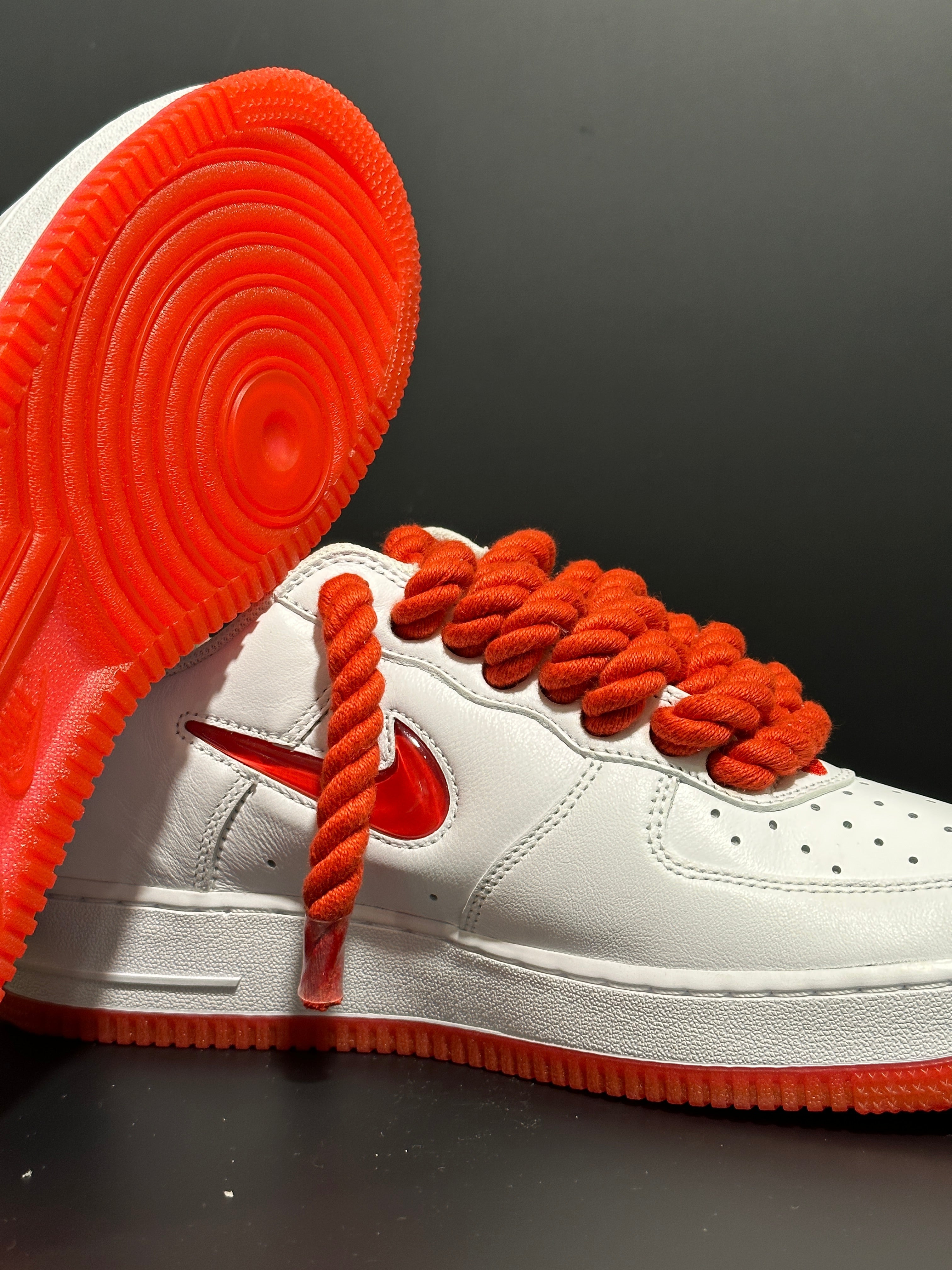 White leather sneaker with thick red rope laces and red sole, modern streetwear style