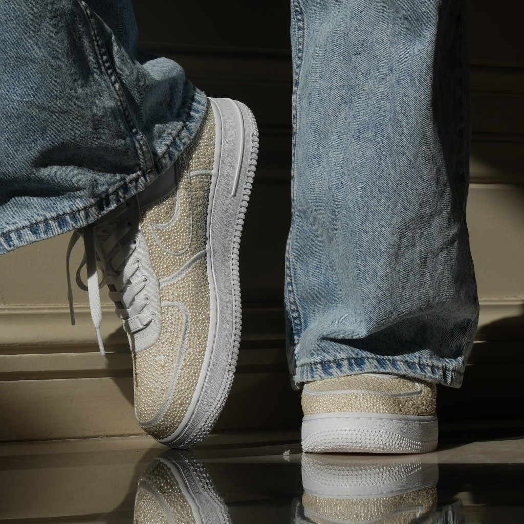 Beige designer sneakers with textured details worn with loose fit jeans, streetwear style