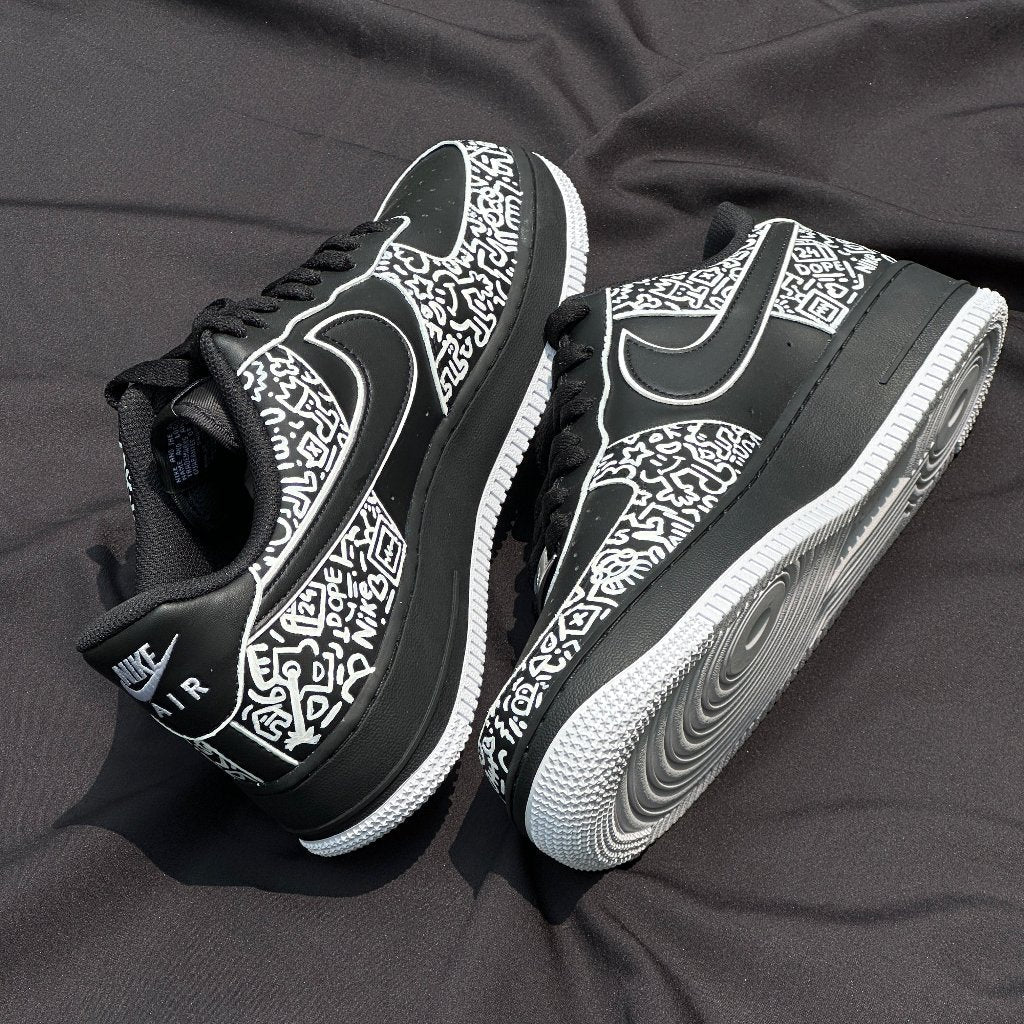 Black and white streetwear sneakers with bold graphic patterns and white soles on black fabric.