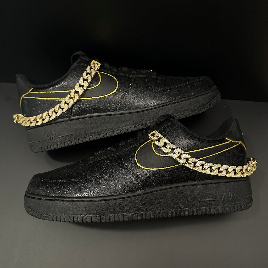 Black streetwear sneakers with gold stitching and a gold chain accent on side, luxury footwear