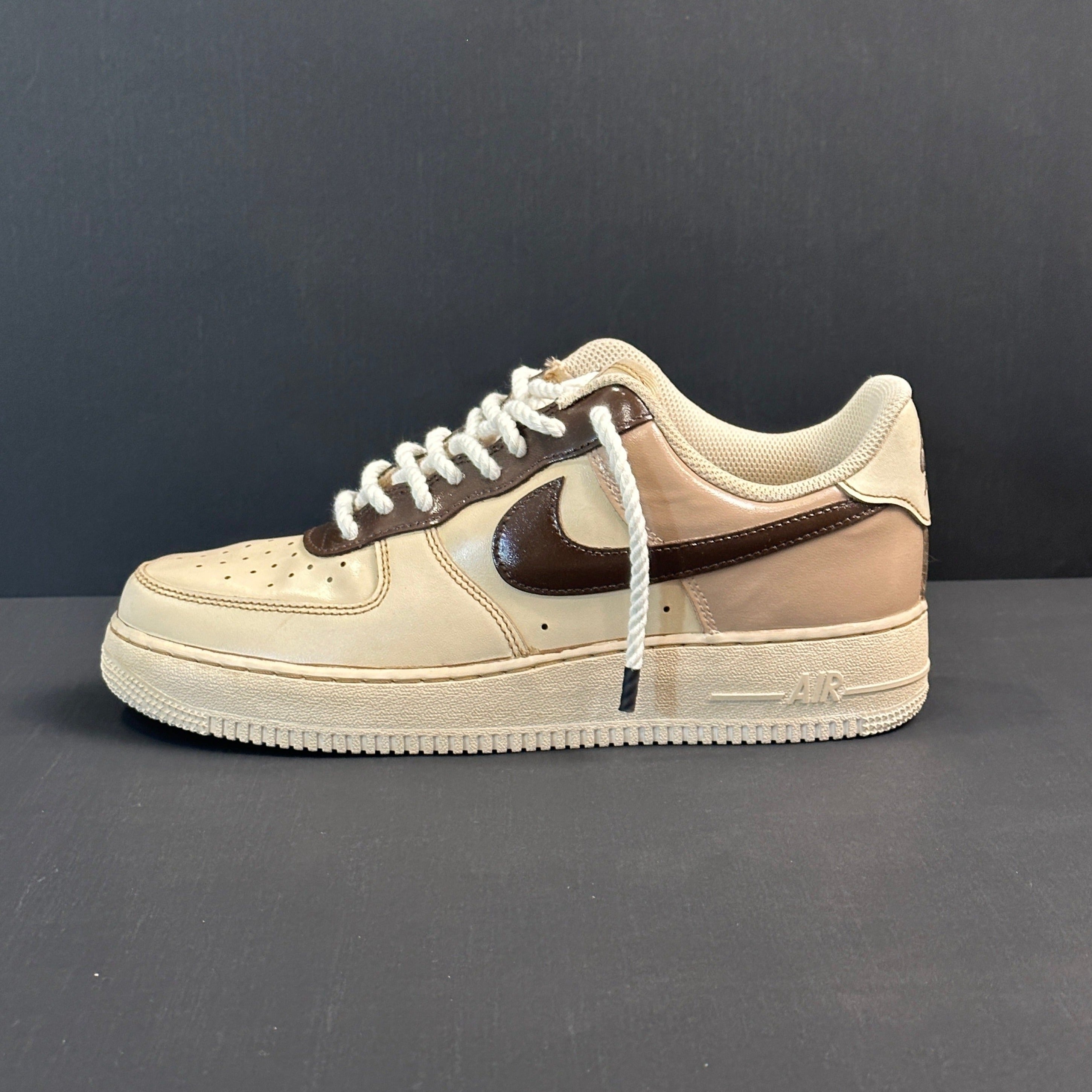 Beige and brown Nike Air Force 1 low-top sneaker with white laces on gray background