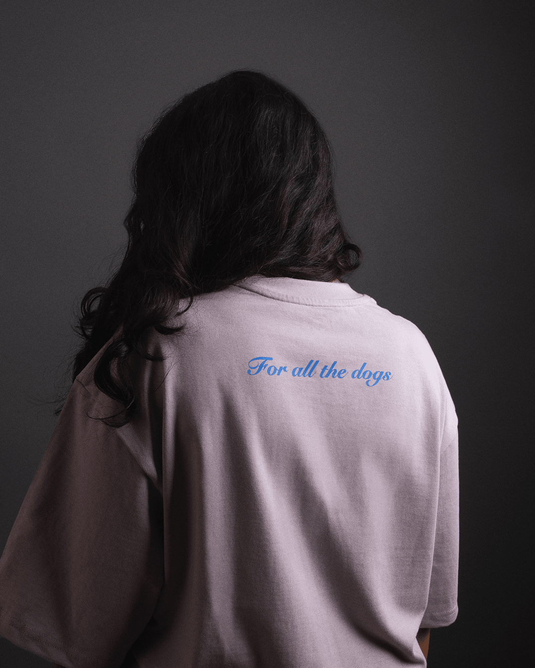 Back view of a person wearing a lavender streetwear t-shirt with 'For all the dogs' text